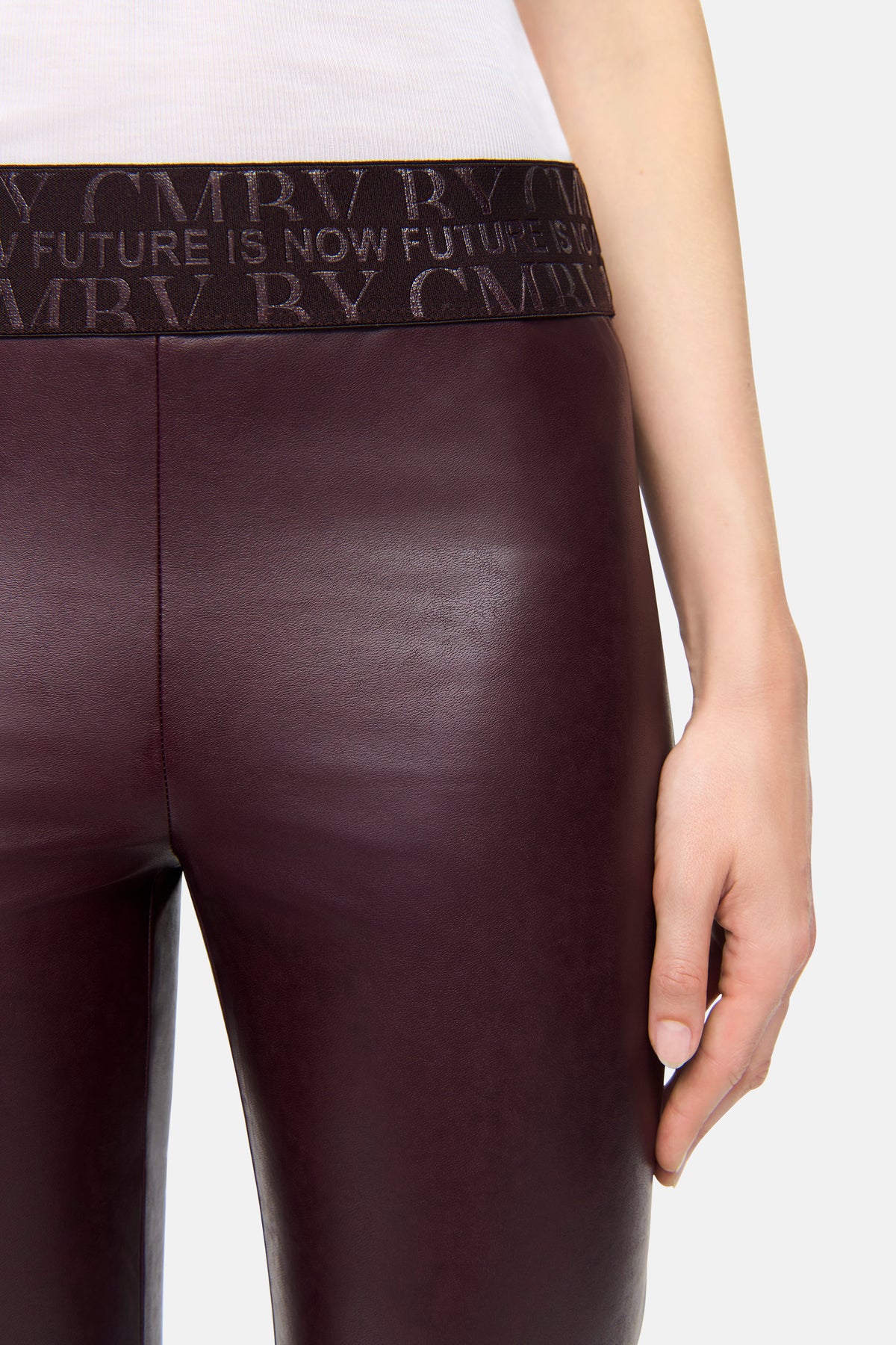 Bordeauxfarbene Skinny-Fit Hose aus veganem Nappa mit elastischem Wordingbund, getragen von einer Person in naher Ansicht.