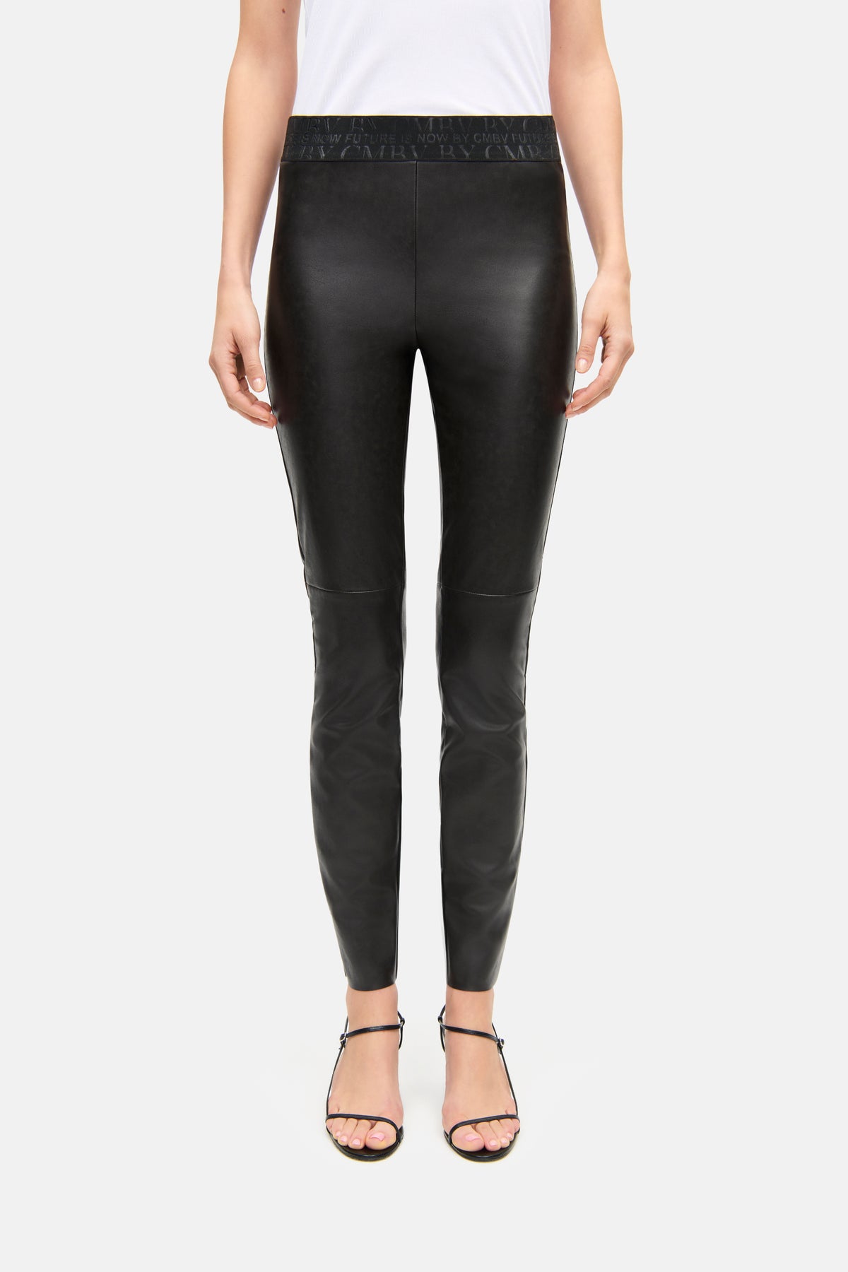 Schwarze Skinny-Fit-Hose aus veganem Nappa mit elastischem Bündchen. Getragen von einer Person mit Sandalen.