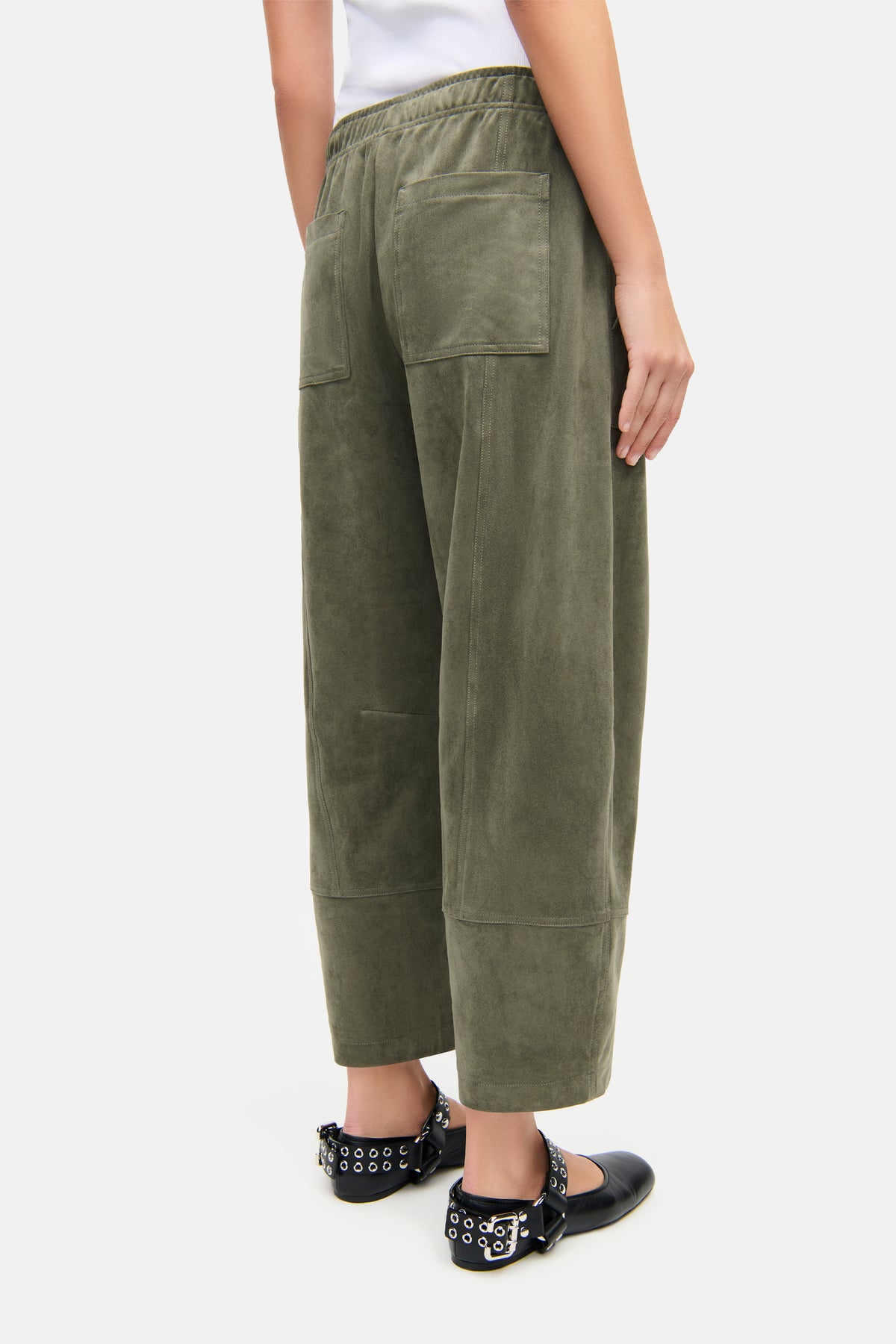 Grüne, o-förmige, verkürzte Hose aus veganem Velours mit Komfortbund und großen Fronttaschen, getragen von einer Person. Material: 92% Polyester, 8% Elasthan.