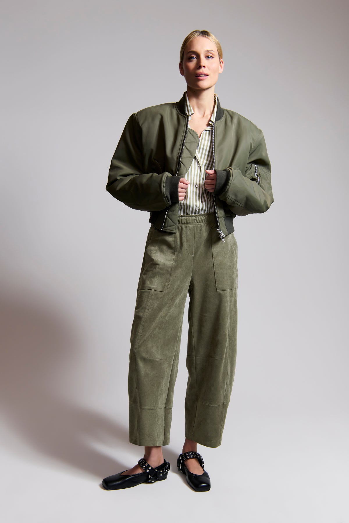 Grüne O-Shape-Hose aus veganem Velours, 92% Polyester und 8% Elasthan. Getragen in einer urbanen, modischen Umgebung.