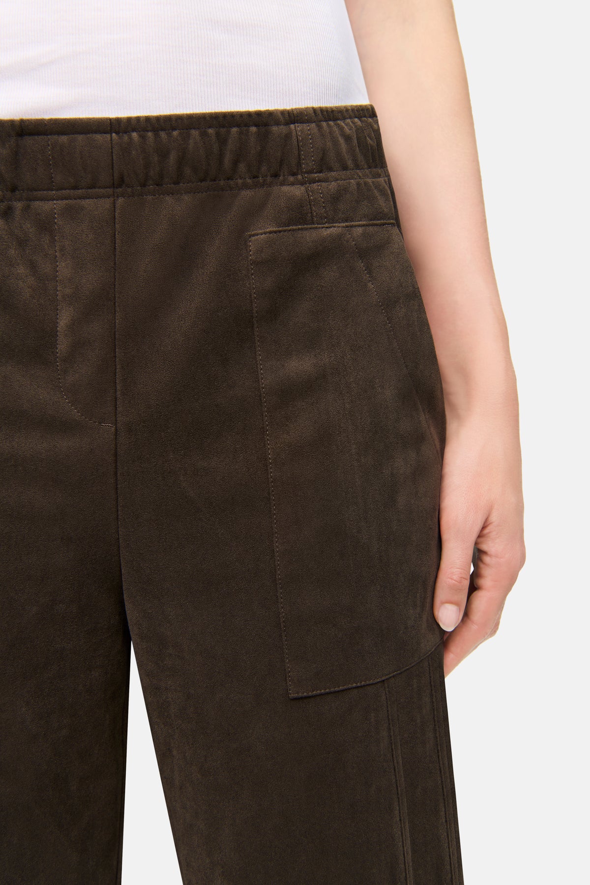 Dunkelbraune O-Shape Hose aus veganem Velours, 92% Polyester, 8% Elasthan. Getragen in einem Alltagssetting.