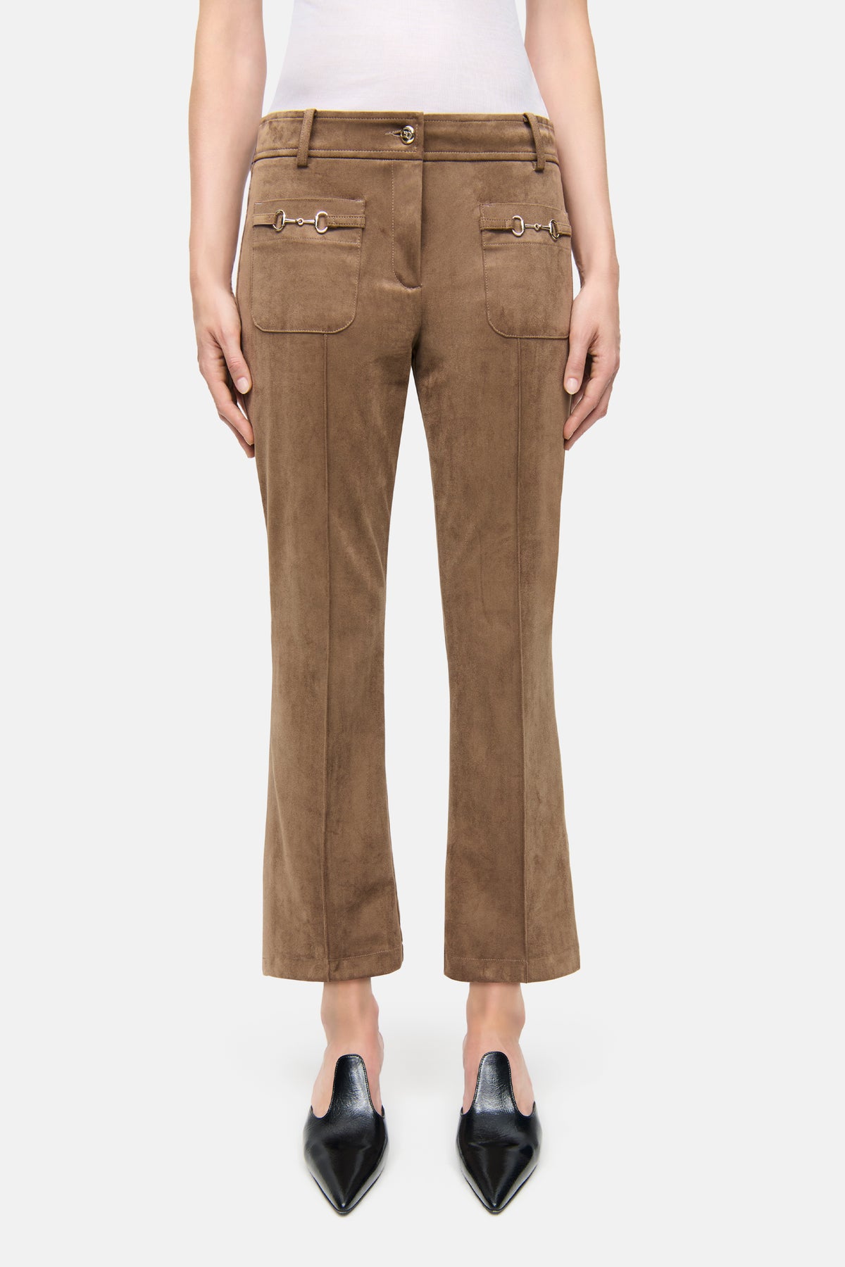 Flared Hose in Braun, aus veganem Veloursleder, mit dekorativen Vordertaschen und silberfarbenen Details, getragen von einer Person.