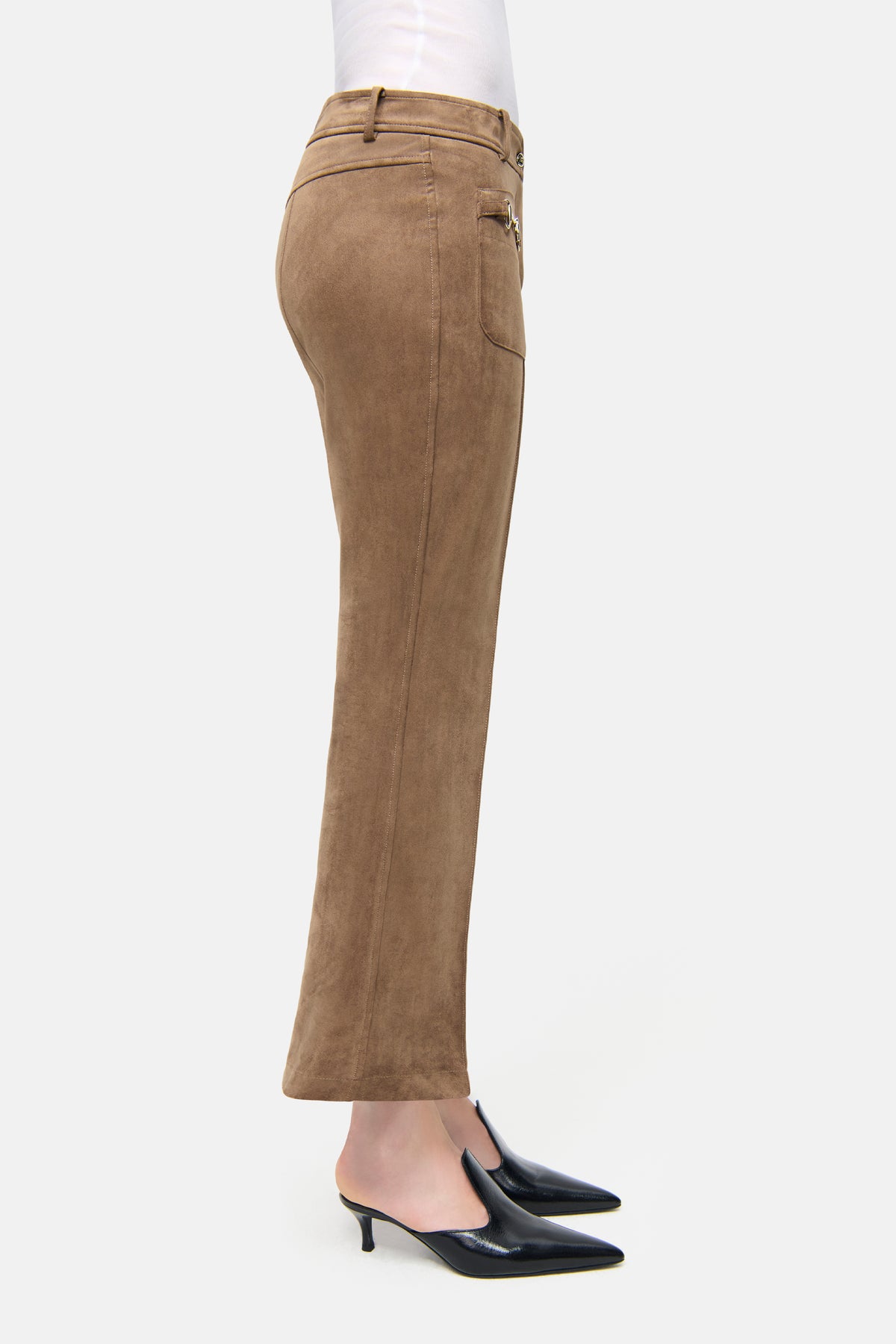 Braune Flared-Hose aus veganem Veloursleder, getragen in einem neutralen Innenraum. Dekorative Vordertaschen sichtbar.