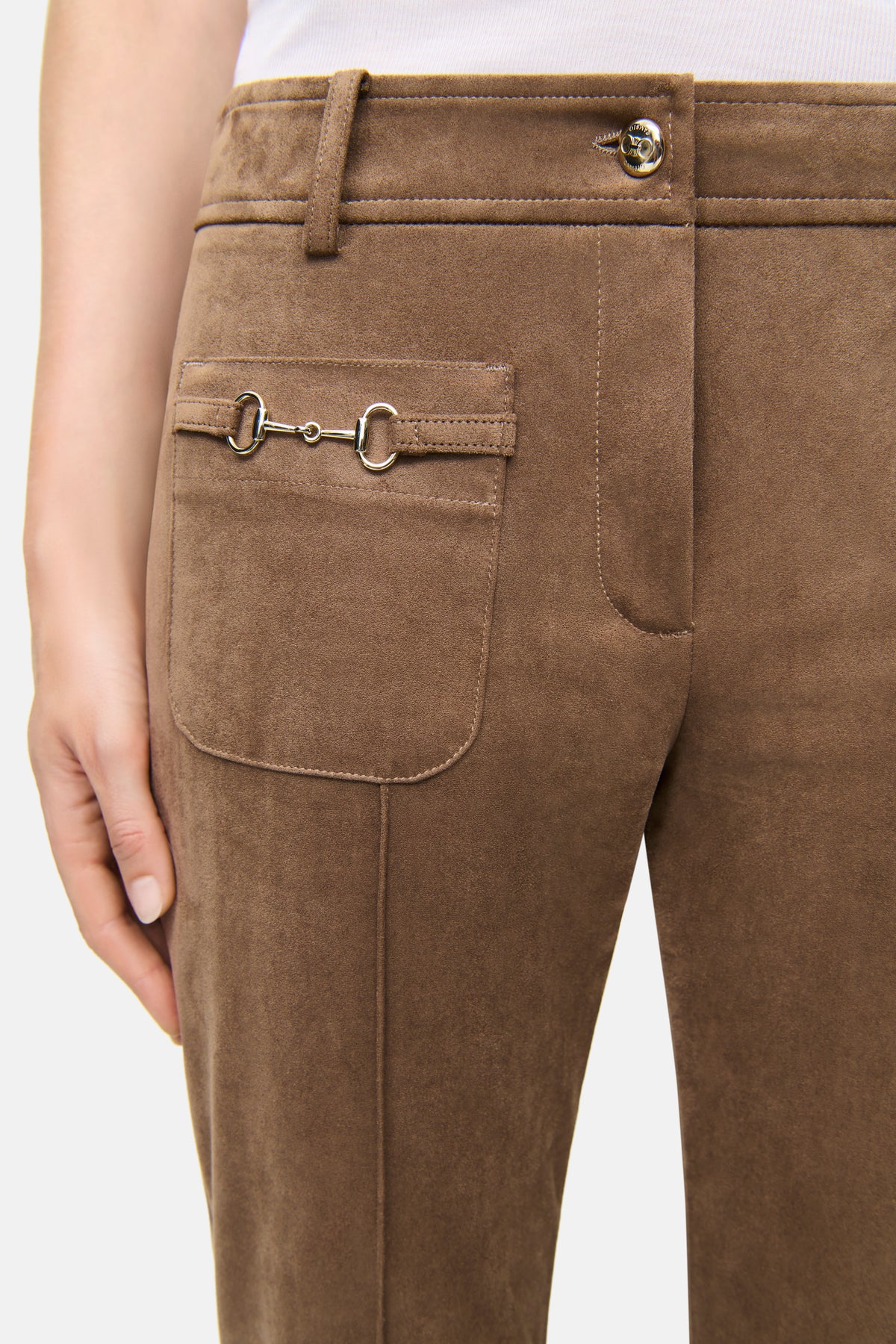 Braune Flared-Hose aus veganem Veloursleder mit aufgesetzten Nähten und dekorativen Vordertaschen, von einer Person getragen.