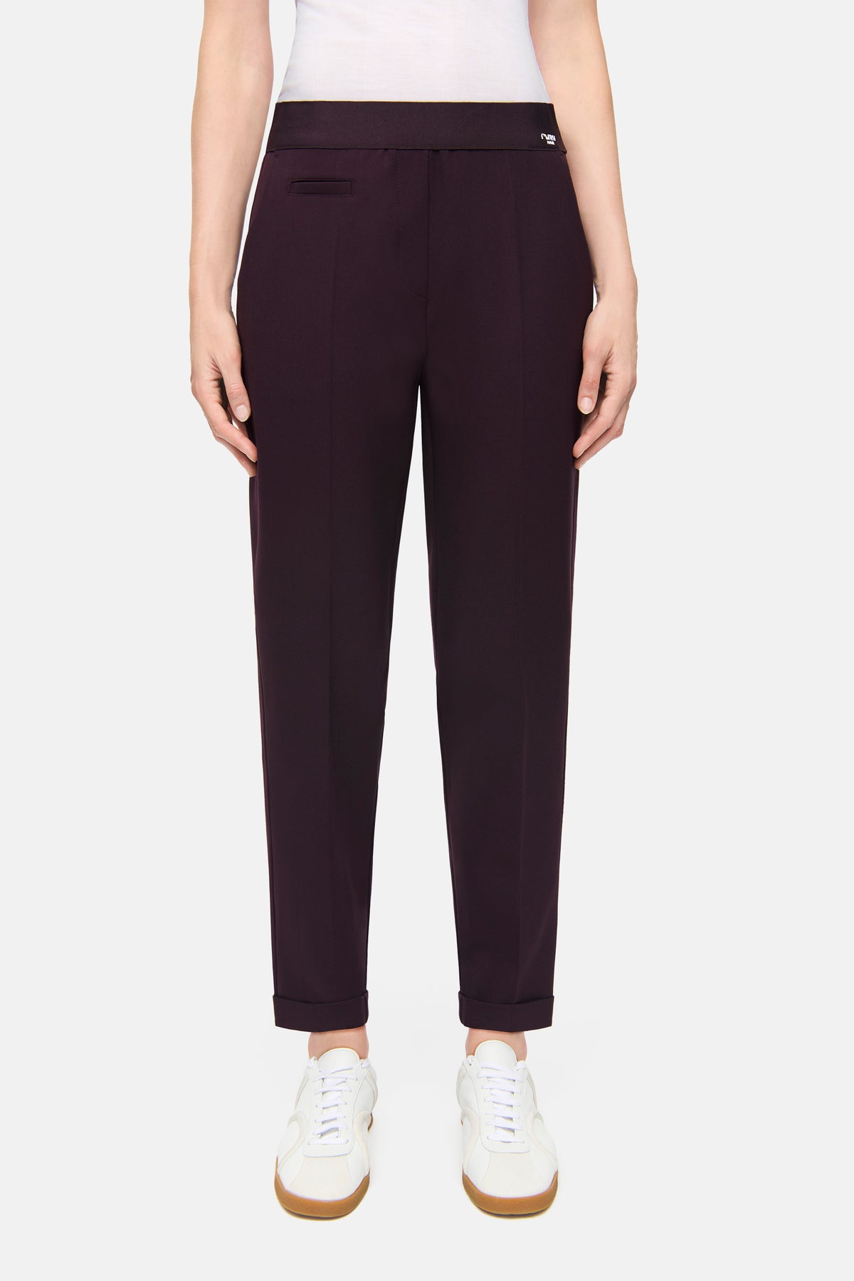 Bordeauxfarbige Karottenhose aus 63% Polyester, 27% Viskose, 7% Baumwolle, 3% Elasthan, getragen von einer Person in Alltagskleidung.