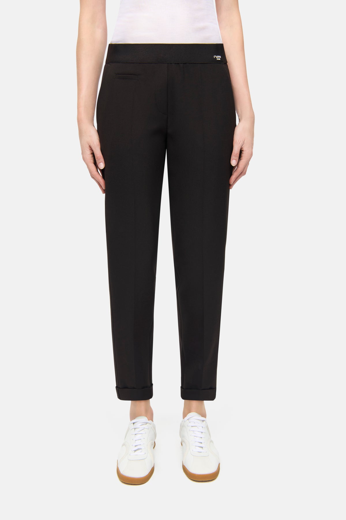 Dunkelbraune Karottenhose aus 63% Polyester, 27% Viskose, 7% Baumwolle, 3% Elasthan, getragen von einer Person in weißem Schuhwerk.