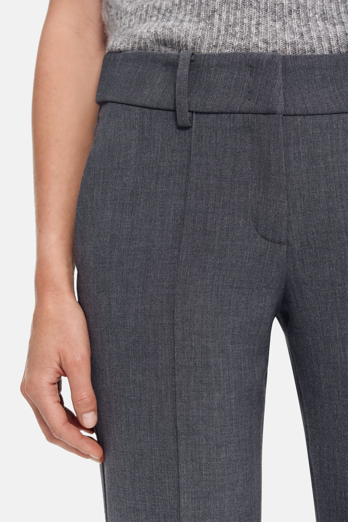 Graue, flared Hose aus 63% Polyester, 27% Viskose, 7% Baumwolle, 3% Elasthan, getragen in einer urbanen Umgebung.