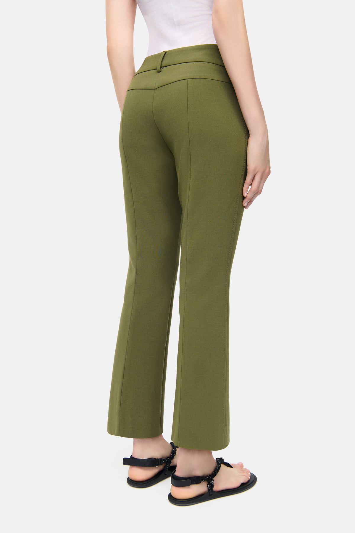 Grüne Flared-Hose in verkürzter Länge, Material: 7% Baumwolle, 63% Polyester, 3% Elasthan, 27% Viskose. Getragen in einem Freizeitsetting.