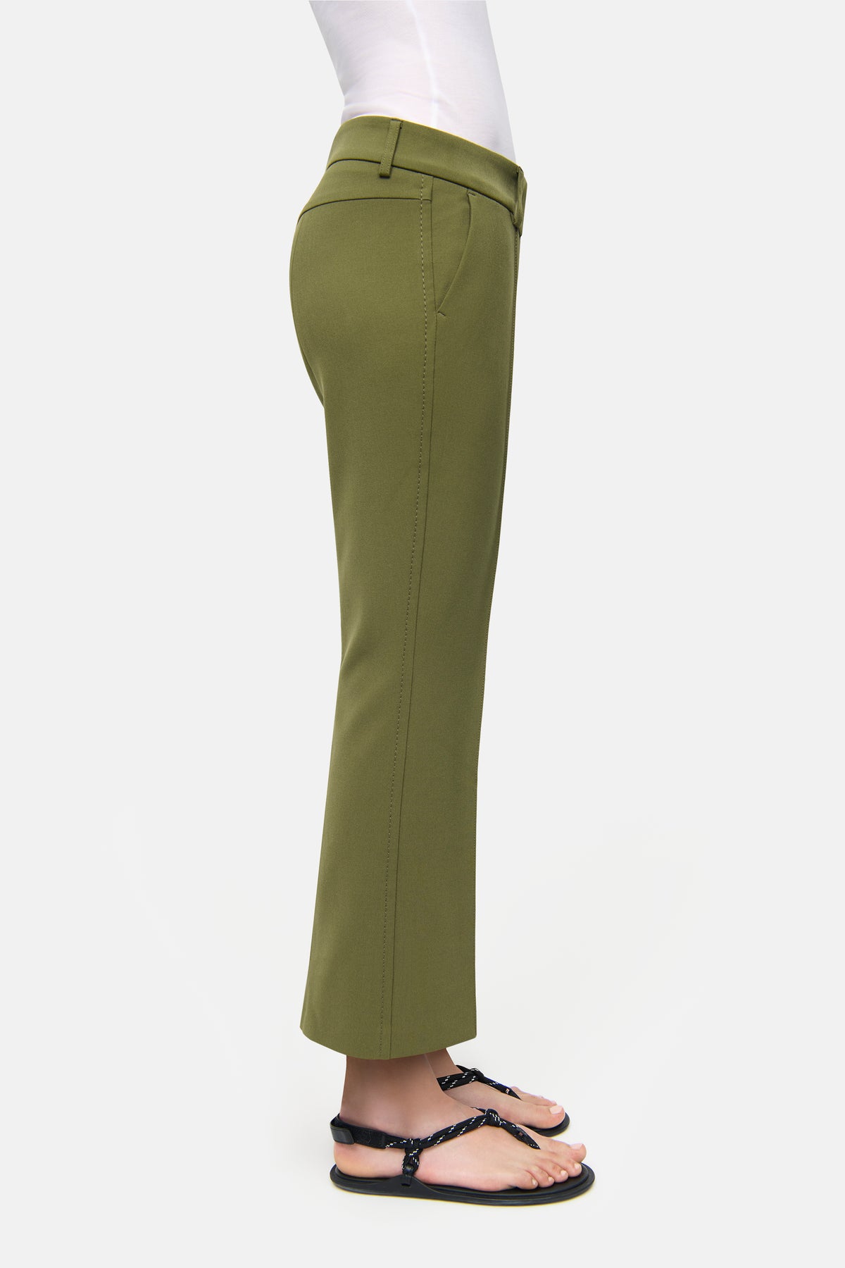 Grüne, verkürzte Flared-Hose aus 7% Baumwolle, 63% Polyester, 3% Elasthan und 27% Viscose, im urbanen Umfeld getragen.