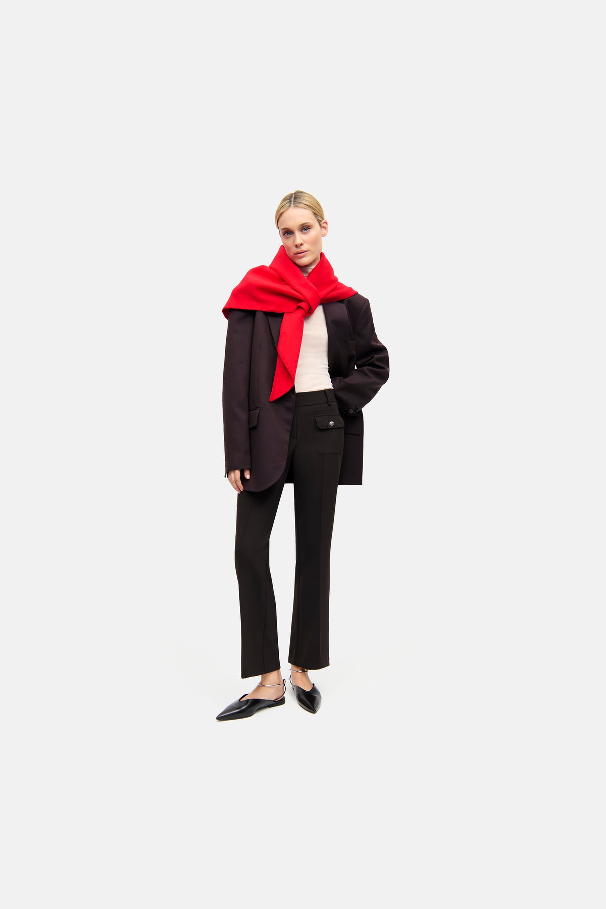 Flared-Fit Hose in dunkelbraunem "Black Coffee" Ton, aus 7% Baumwolle, 63% Polyester, 3% Elasthan, 27% Viskose. Getragen in einem urbanen Stil mit rotem Schal und schwarzem Blazer.