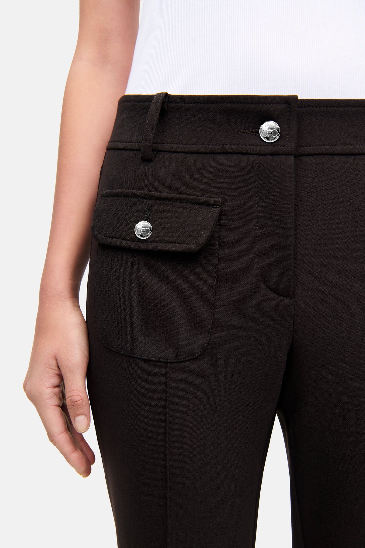 Dunkelbraune Flared-Hose mit aufgesetzter Fronttasche und silbernen Knöpfen, hergestellt aus Baumwolle, Polyester, Elasthan und Viskose.