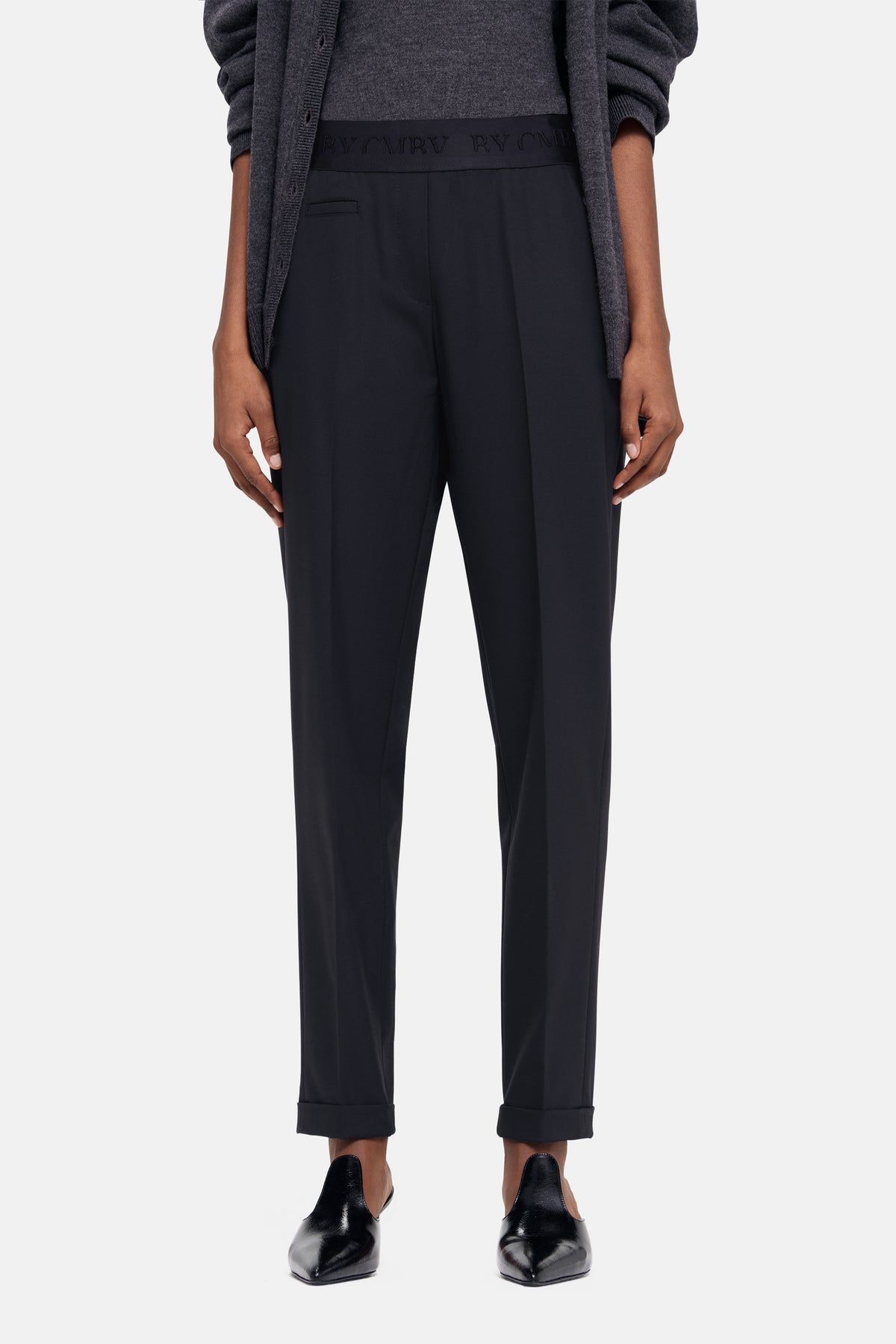 Schwarze Karottenhose aus 67% Polyester, 29% Viskose, 4% Elasthan, getragen in einer Szene mit lässigem, eleganten Outfit.