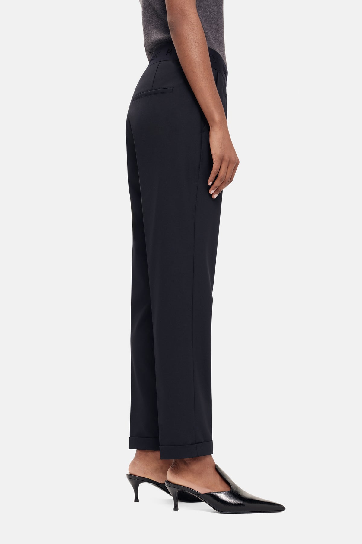 Schwarze Karottenhose aus 67% Polyester, 29% Viskose, 4% Elasthan. Seitliche Ansicht mit umgeschlagenem Saum.