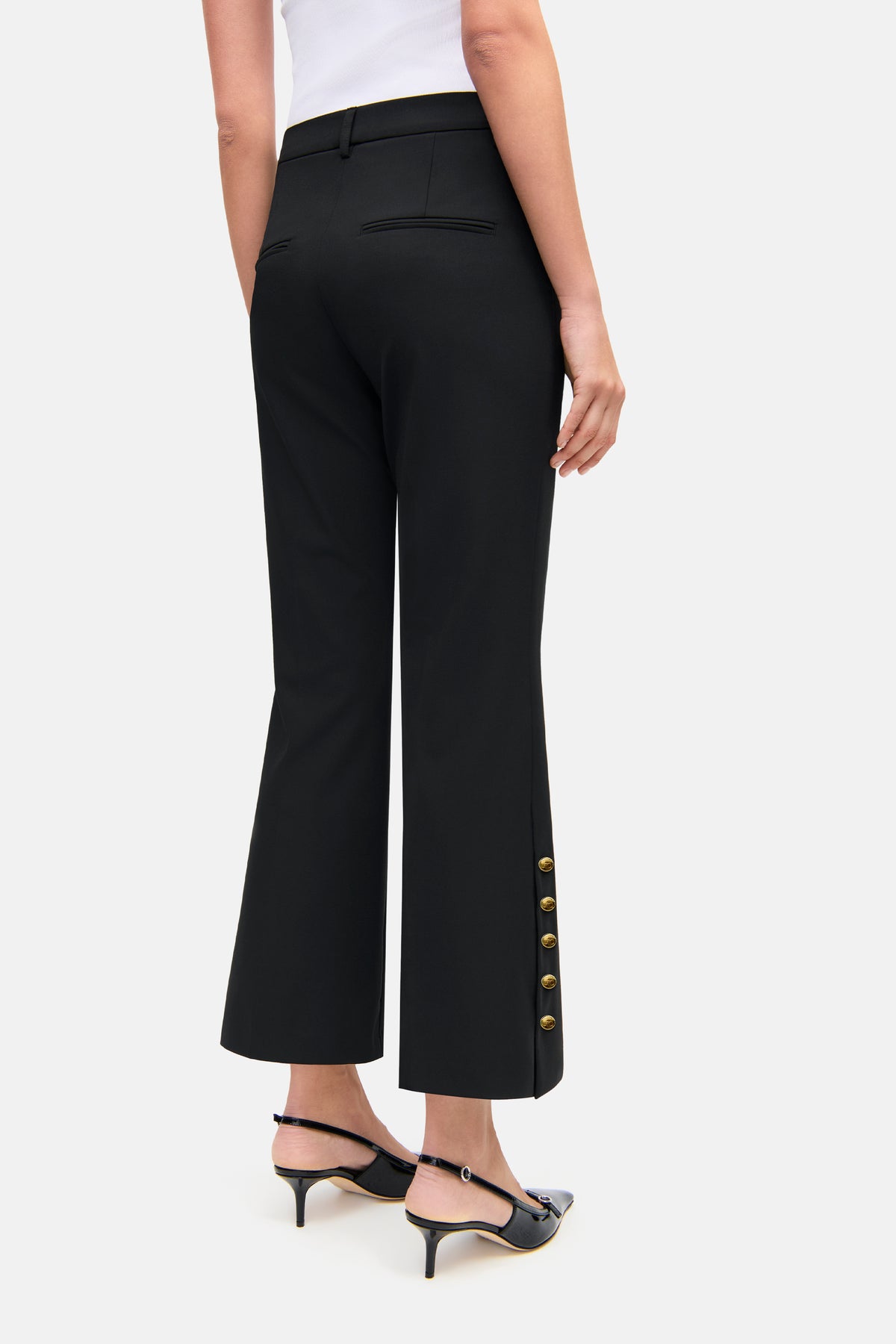 Schwarze flared Cropped-Hose aus 67 % Polyester, 4 % Elasthan, 29 % Viskose, mit goldenen Knöpfen an der Seitennaht.
