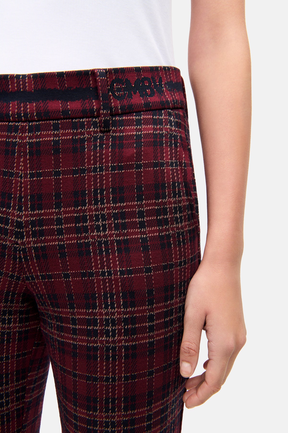 Bordeauxfarbene, karierte Hose im Flared-Fit-Stil, aus Viskose-Mischstoff, getragen in einem urbanen Rahmen.