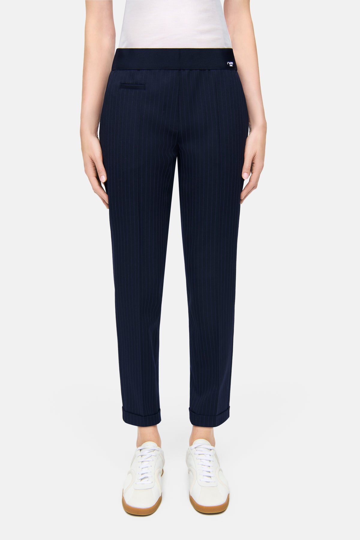 Dunkelblau gestreifte Karottenhose aus 62% Polyester, 26% Viskose, 9% Wolle, 3% Elasthan. Getragen in urbanem Setting.