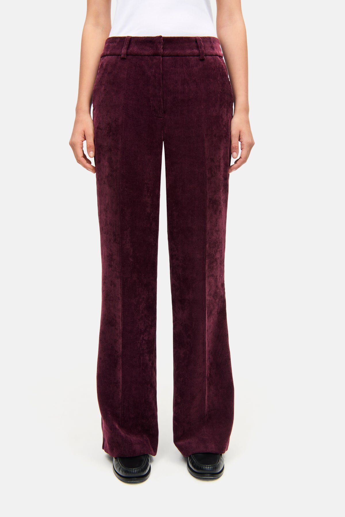 Bordeauxrote Cordhose in weiter Passform, aus 90% Polyester, 8% Polyamid und 2% Elasthan. Getragen in einem lässigen, urbanen Stil.