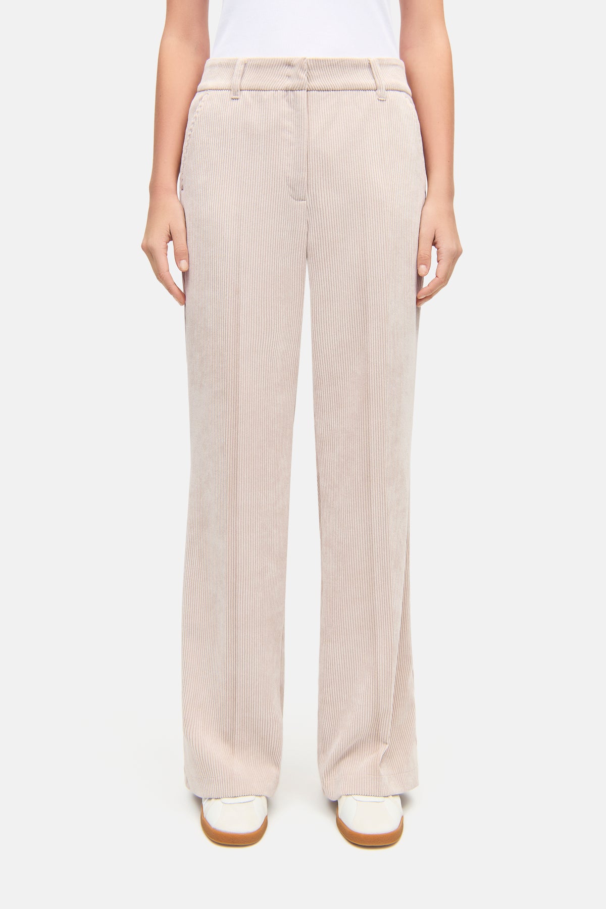 Cremefarbene Cordhose mit weitem Bein, hergestellt aus 90% Polyester, 8% Polyamid und 2% Elasthan, getragen von einer Person.