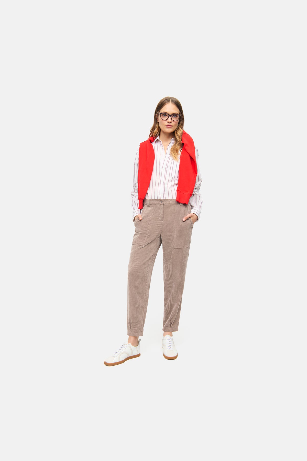 Braune Cordhose in Karotten-Silhouette, 90% Polyester, 8% Polyamid, 2% Elasthan. Person trägt Hemd und Sneaker.