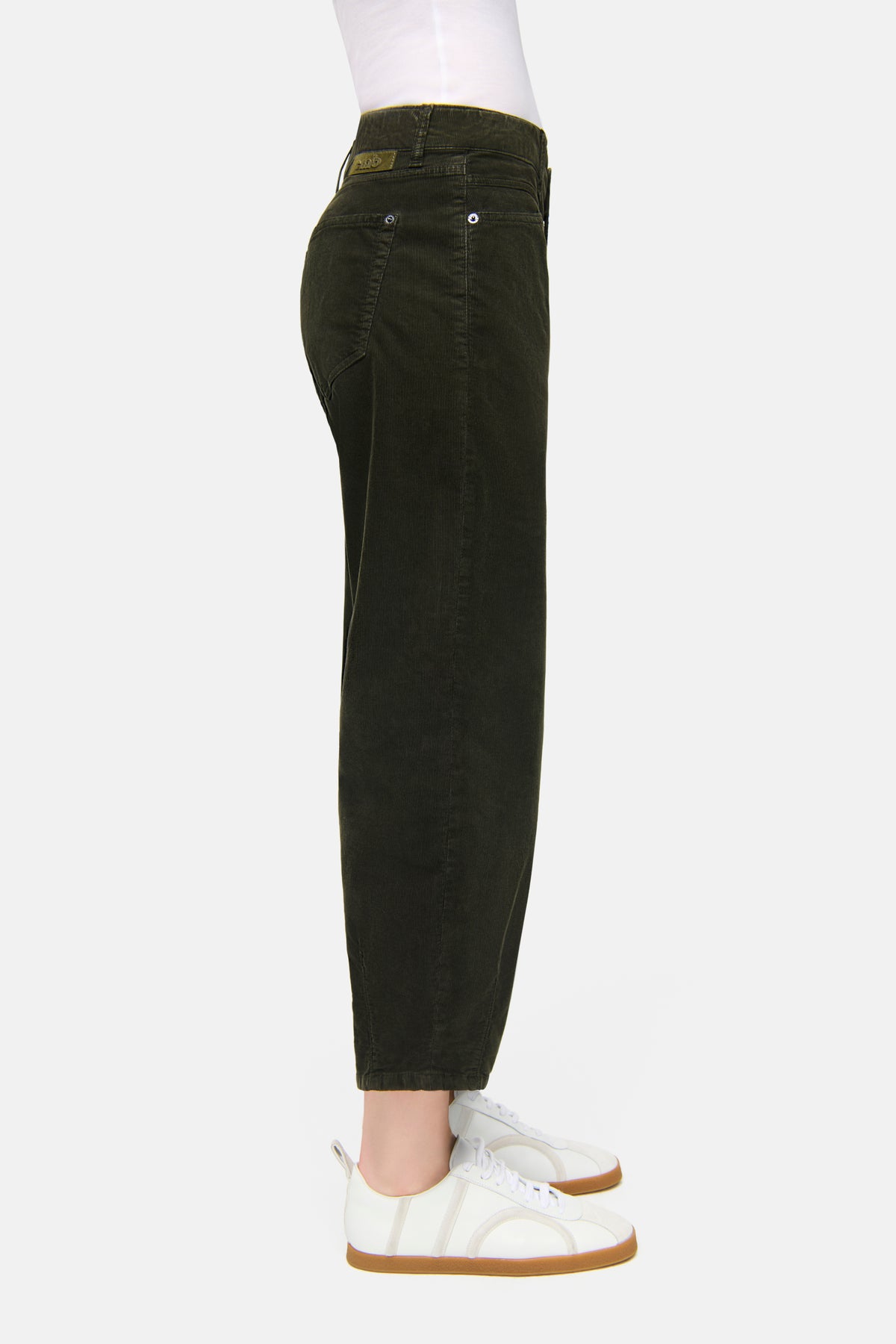 Grüne O-Shape Feincordhose, verkürzte Länge, aus 97% Baumwolle, 3% Elasthan, getragen mit weißen Turnschuhen.