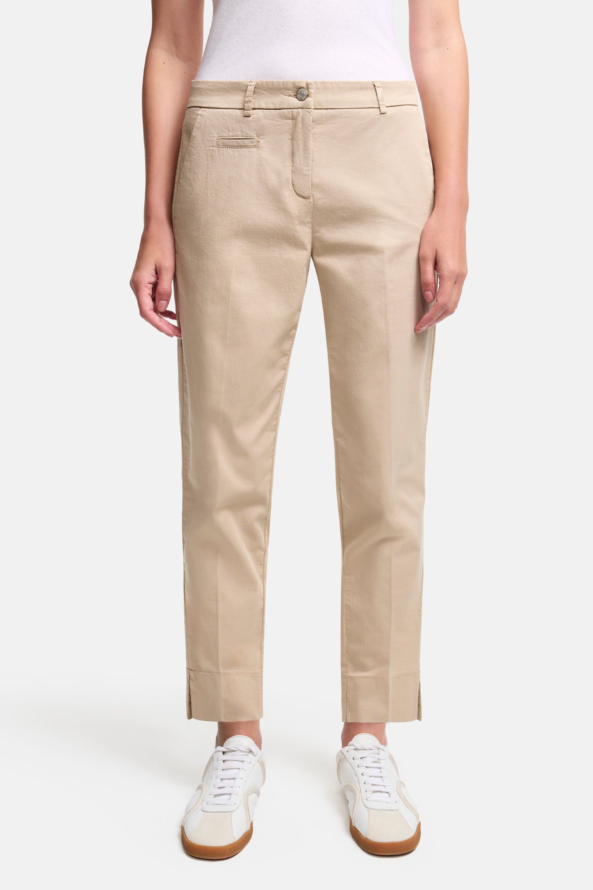 Beige Slim-Fit-Hose aus 97% Baumwolle und 3% Elasthan, im verkürzten Stil "Stella". Getragen mit weißem Oberteil und Sneakern.