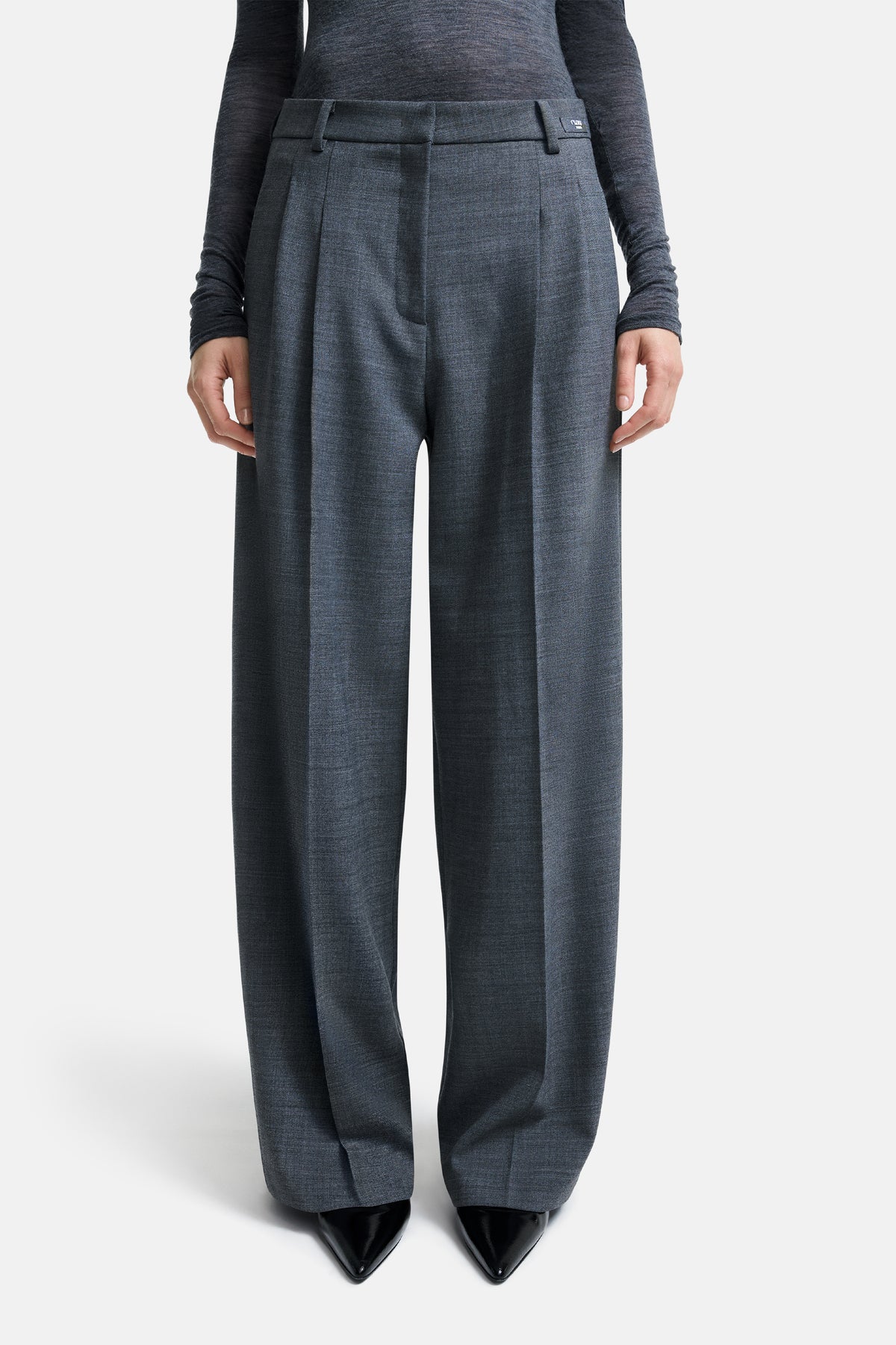 Graue Melange-Hose in weitem Schnitt, aus 53 % Polyester, 43 % Wolle, 4 % Elasthan. Getragen von einer Person in einem minimalistischen, modernen Kontext.