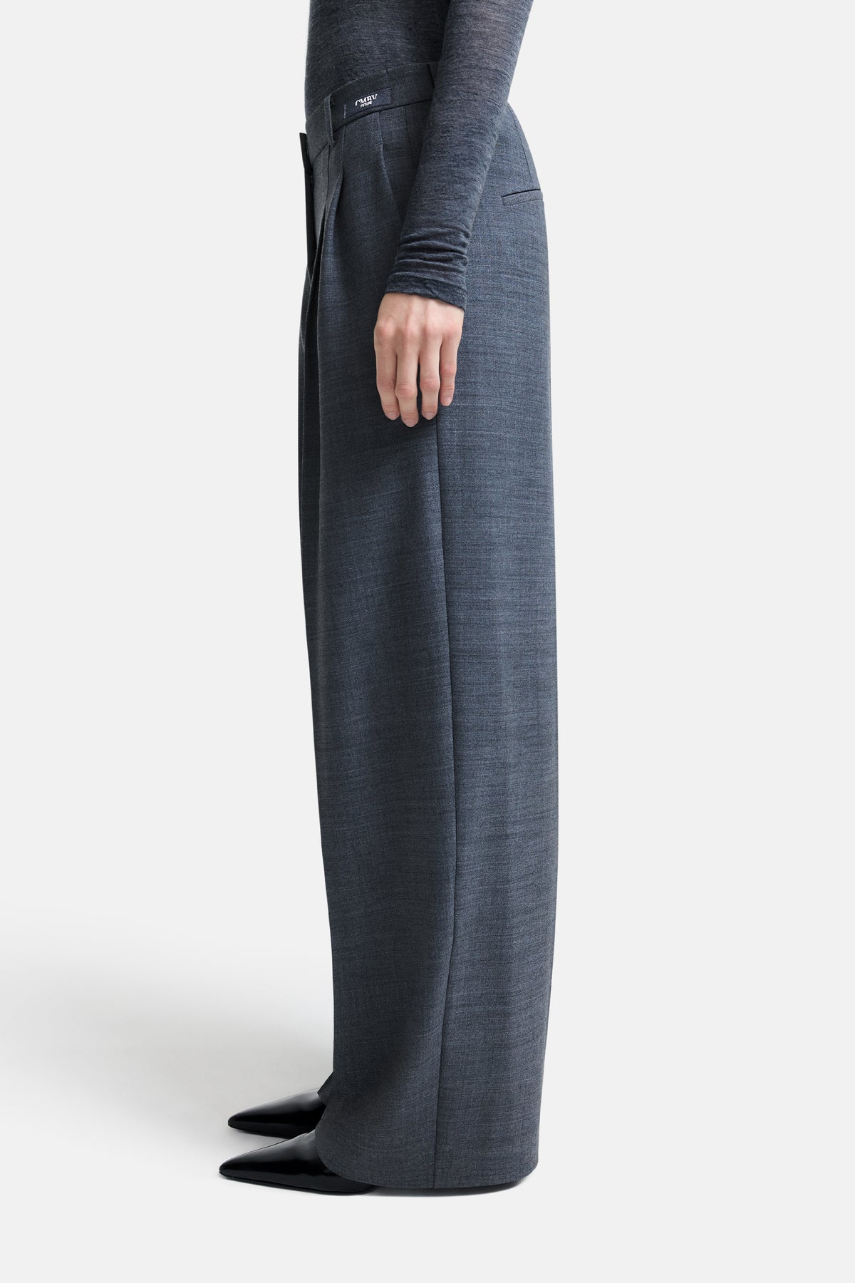 Graue Melange-Hose im Wide-Fit-Design aus 53 % Polyester, 43 % Wolle und 4 % Elasthan, getragen in einem minimalistischen Kontext.