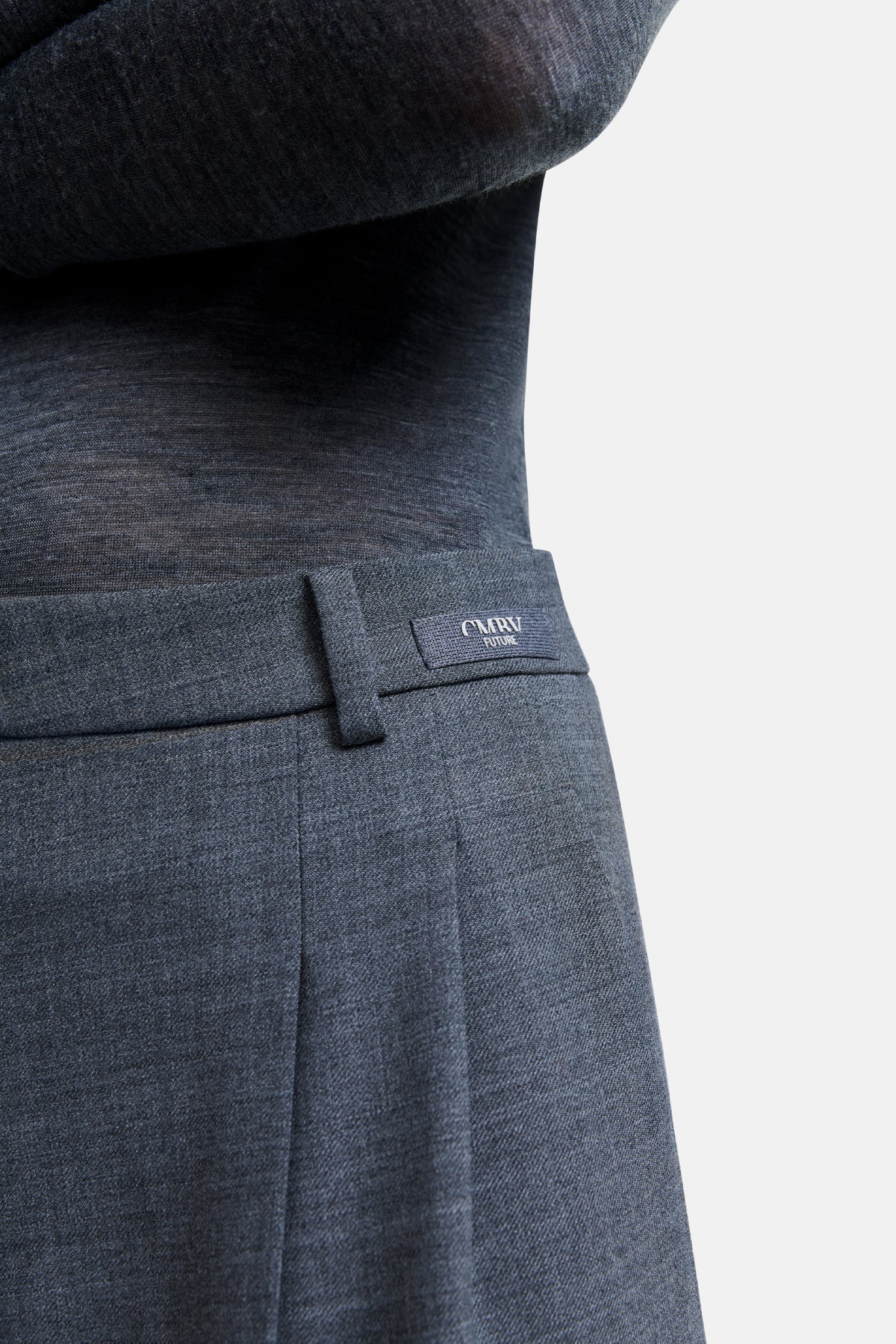 Graue Hose aus 53 % Polyester, 43 % Wolle, 4 % Elasthan, im Wide-Fit-Stil. Getragen im Innenbereich, Detailaufnahme des Bunds.