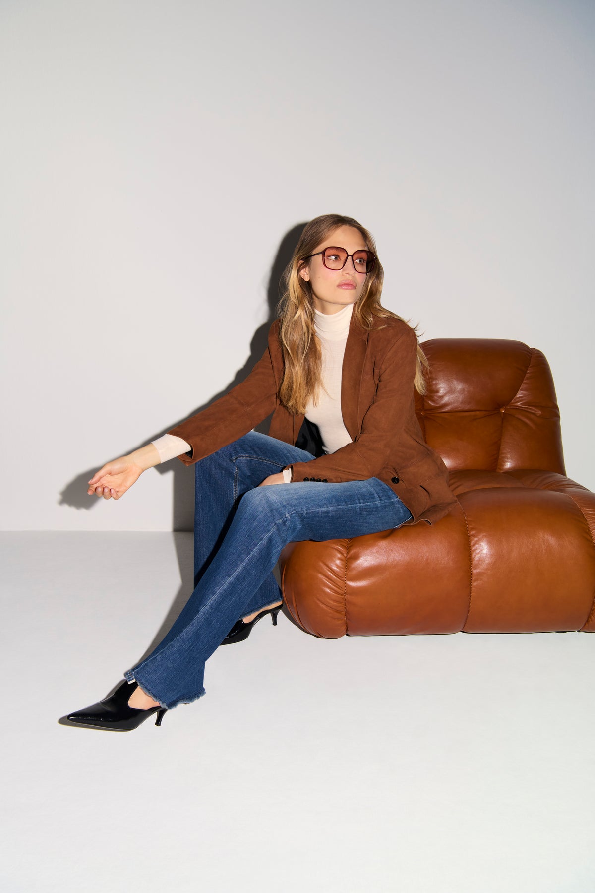 Blaue Flared-Jeans aus 98 % Baumwolle und 2 % Elasthan, getragen in einem modernen Wohnzimmer-Setting.