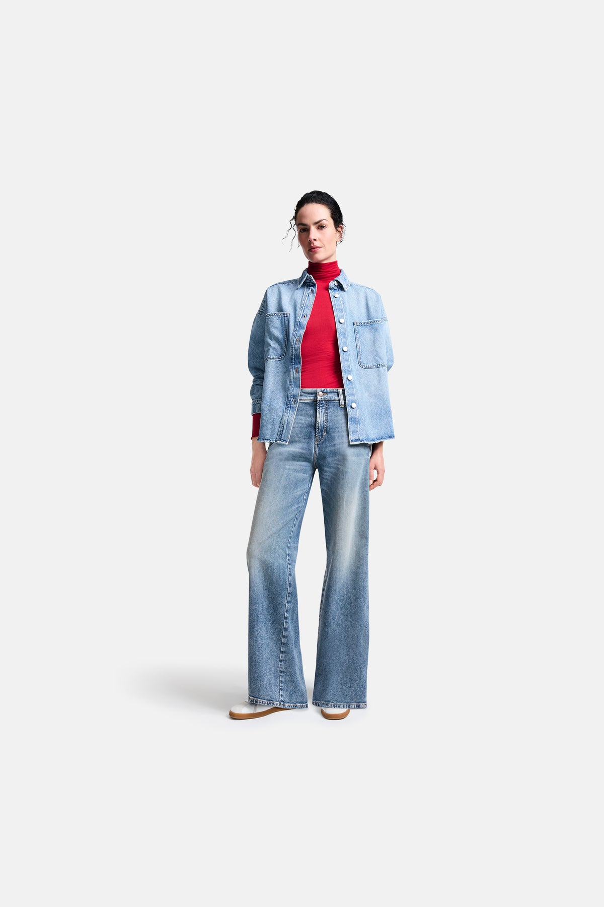 Blaue Wide Leg Jeans in voller Länge aus 98% Baumwolle und 2% Elasthan. Getragen mit einem roten Pullover in urbanem Setting.
