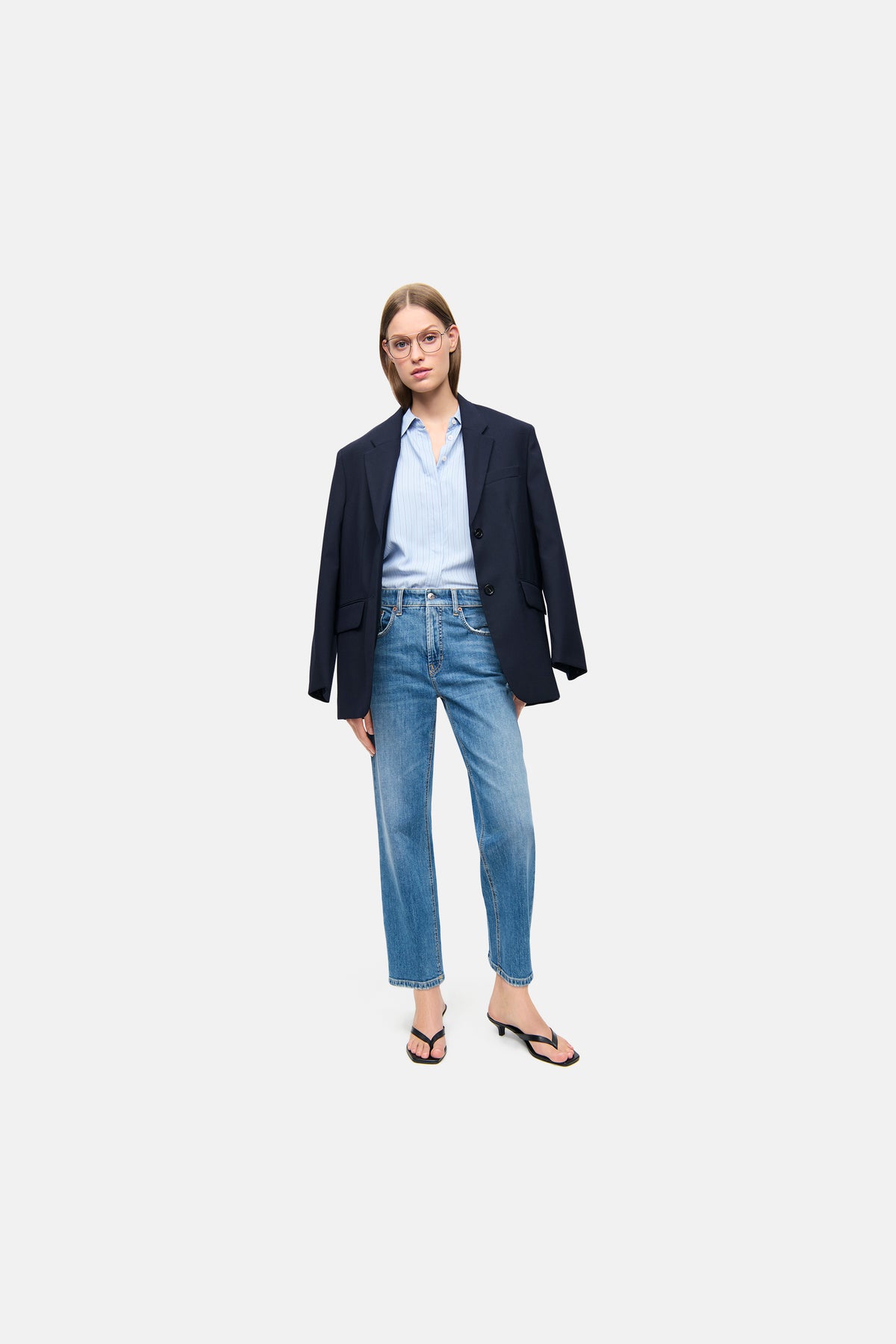 Blaue Straight-Fit Jeans "Gini" aus 98 % Baumwolle und 2 % Elasthan. Getragen mit einer Bluse und einem Blazer.