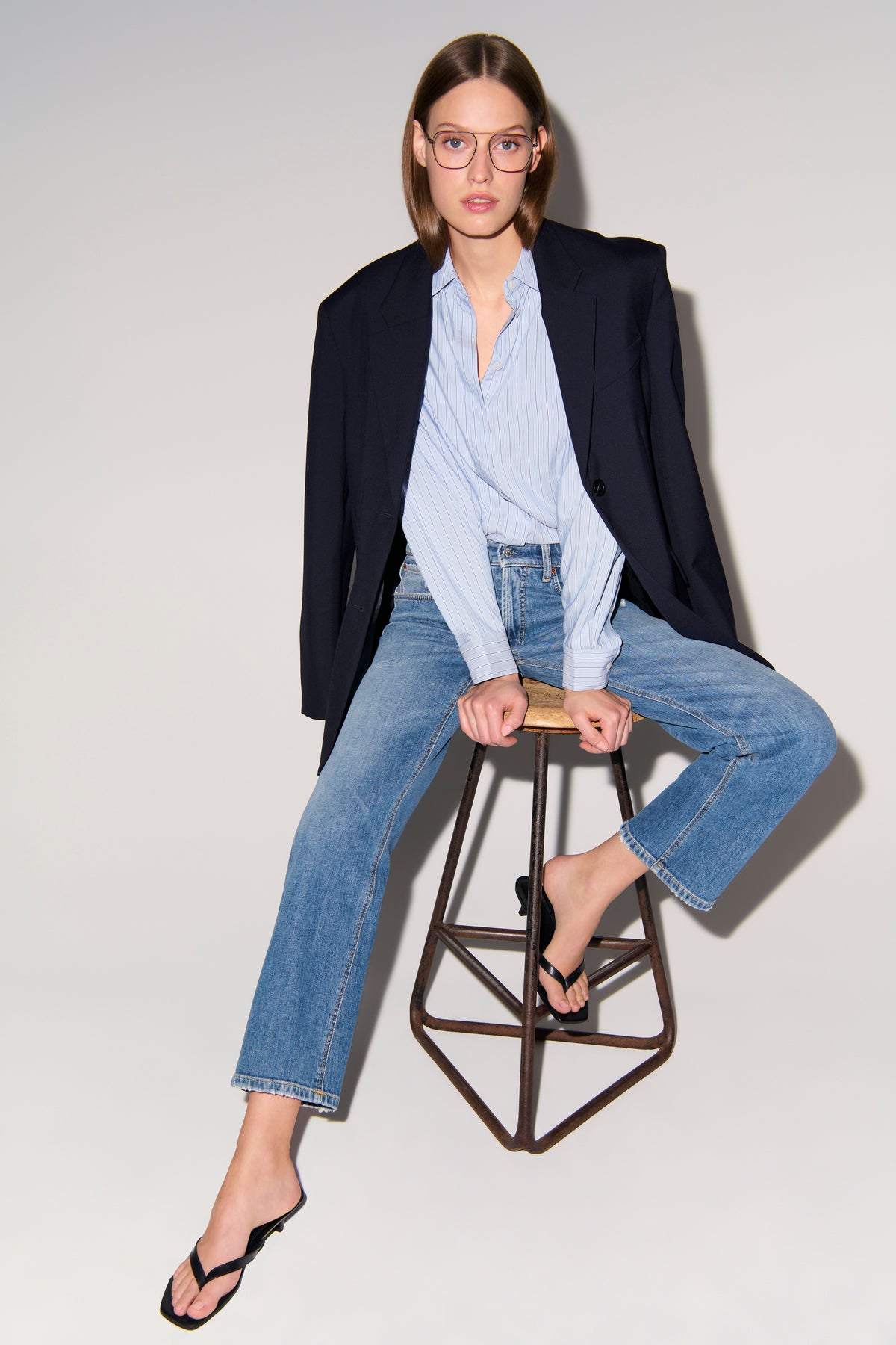 Damenjeans in klassischem Denimblau, gerader Schnitt, Material aus 98% Baumwolle und 2% Elasthan, Frau sitzt auf einem Hocker.