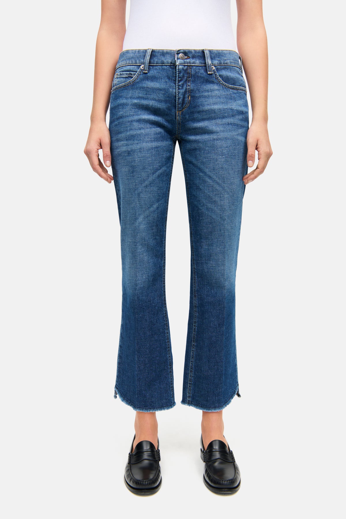 Blaue Flared Jeans mit verkürzter Länge aus 98% Baumwolle und 2% Elasthan, getragen in einem urbanen Setting.