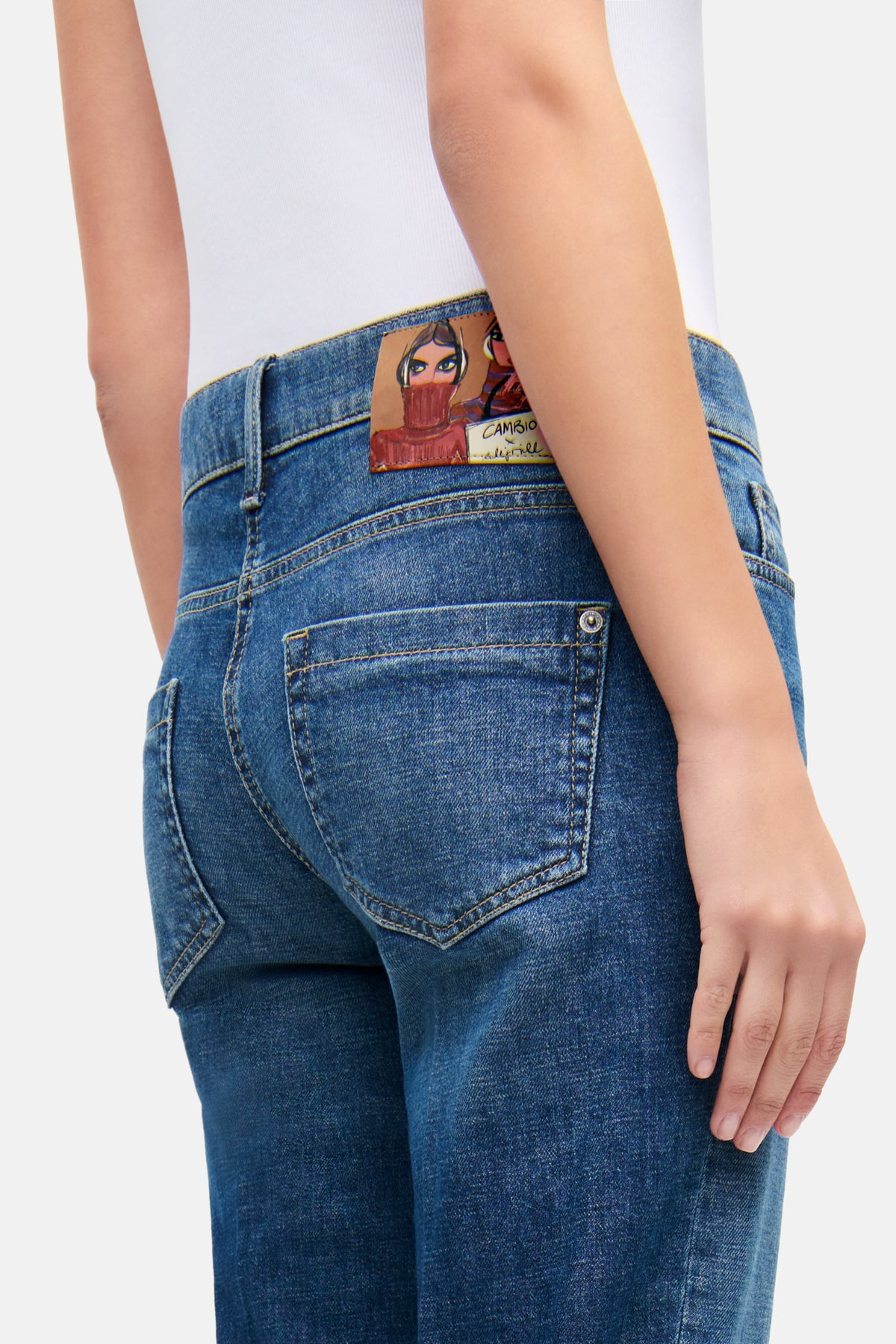 Blaue Flared-Jeans aus 98% Baumwolle und 2% Elasthan, getragen in urbanem Szenario, mit offenem, fransigem Saum.