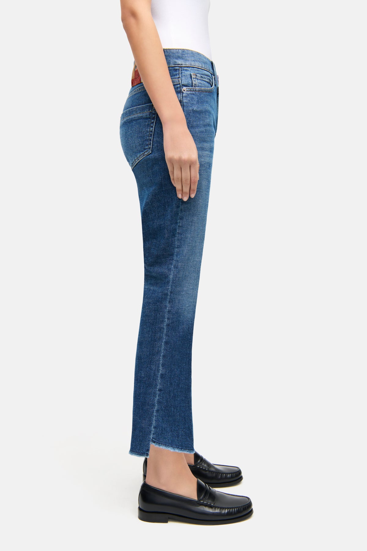 Blaue Flared-Jeans aus 98% Baumwolle und 2% Elasthan, mit offenem, fransigem Saum. Getragen von einer Person, seitliche Ansicht.