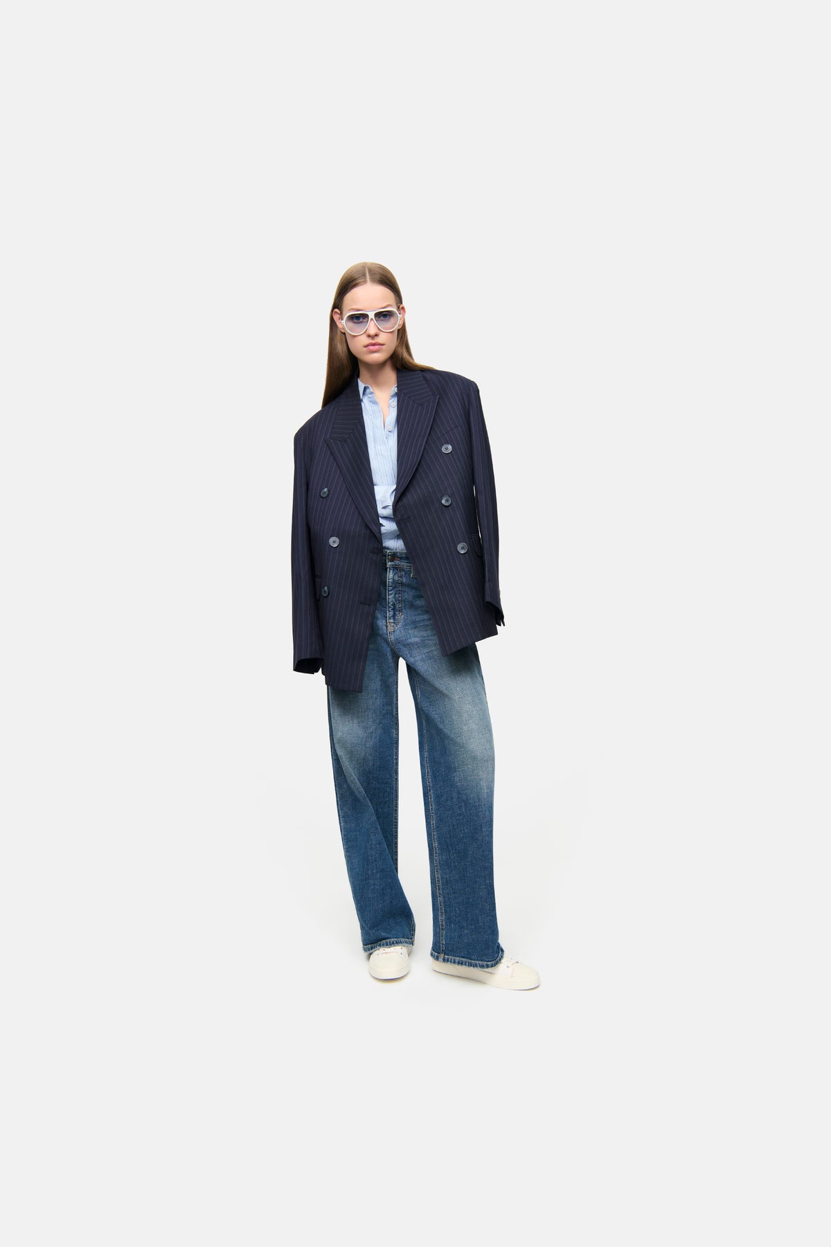 Baggy-Fit-Jeans, blau, aus 98% Baumwolle und 2% Elasthan. Getragen zu einem formellen Outfit mit Blazer und Brille.