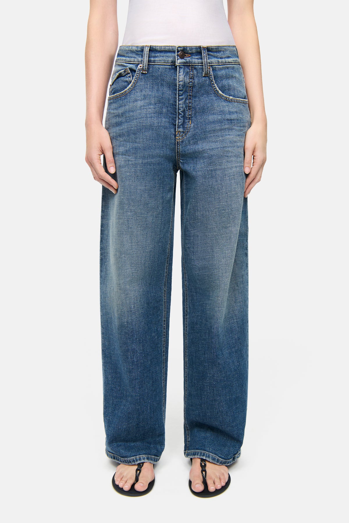 Blaue Baggy-Jeans aus Denim mit weitem Bein und modernem Waschmuster, getragen von Person mit Flip-Flops.