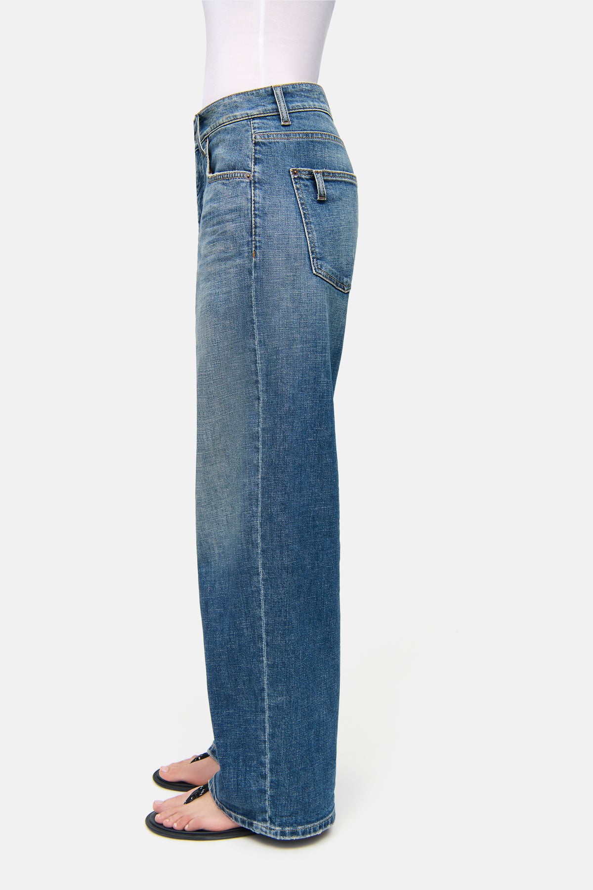 Blaue Baggy-Jeans aus 98% Baumwolle und 2% Elasthan, mit weitem Bein. Getragen von einer Person in einer minimalistischen Umgebung.