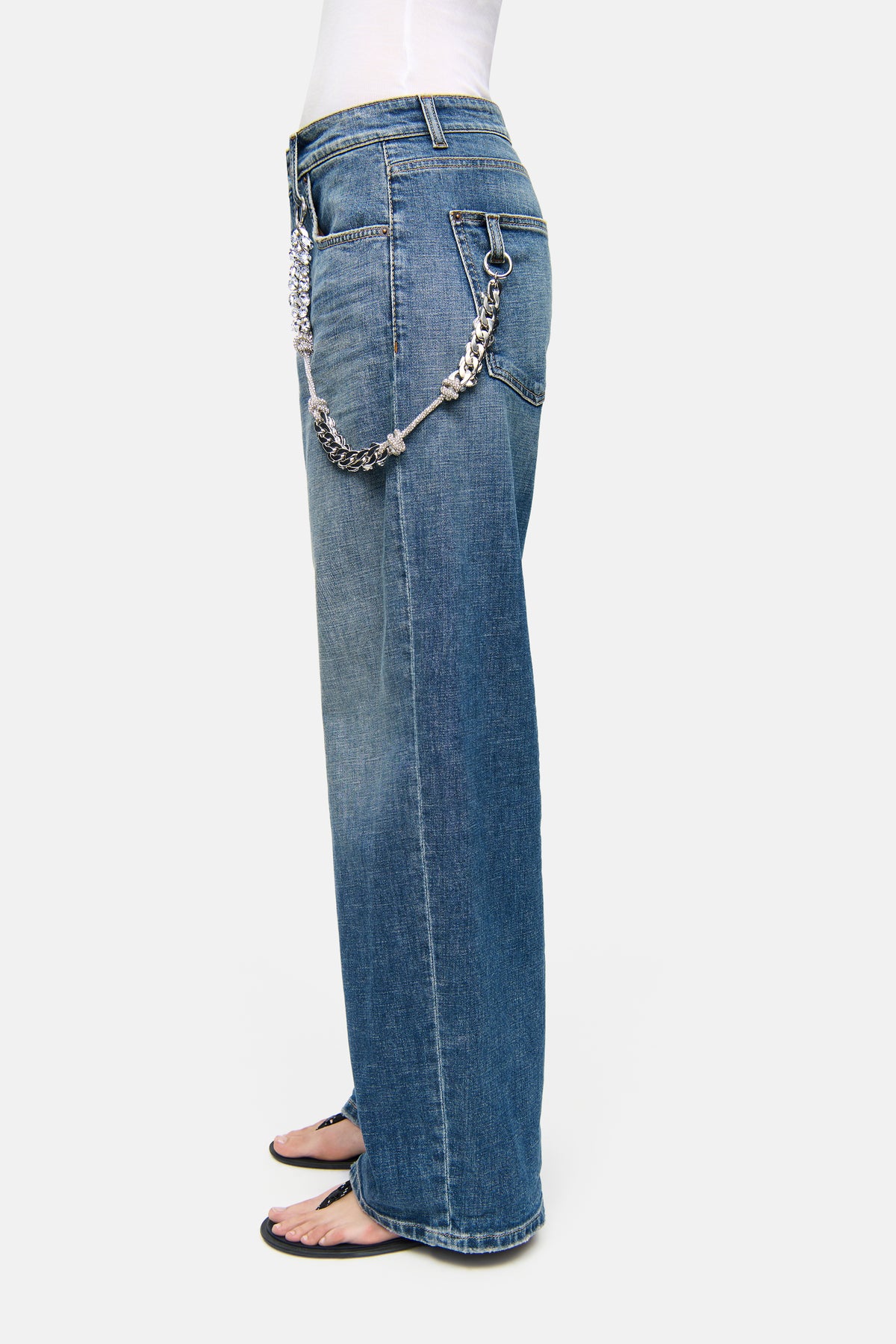 Blaue Baggy-Jeans aus 98% Baumwolle und 2% Elasthan, im urbanen Stil, mit Strasskette an der Seite, seitlicher Blickwinkel.