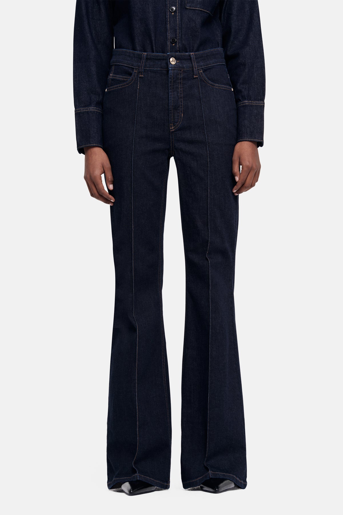 Dunkelblaue Jeans im Flared-Fit aus 93 % Baumwolle, 5 % Polyester, 2 % Elasthan. Getragen in einem Studio-Setting.