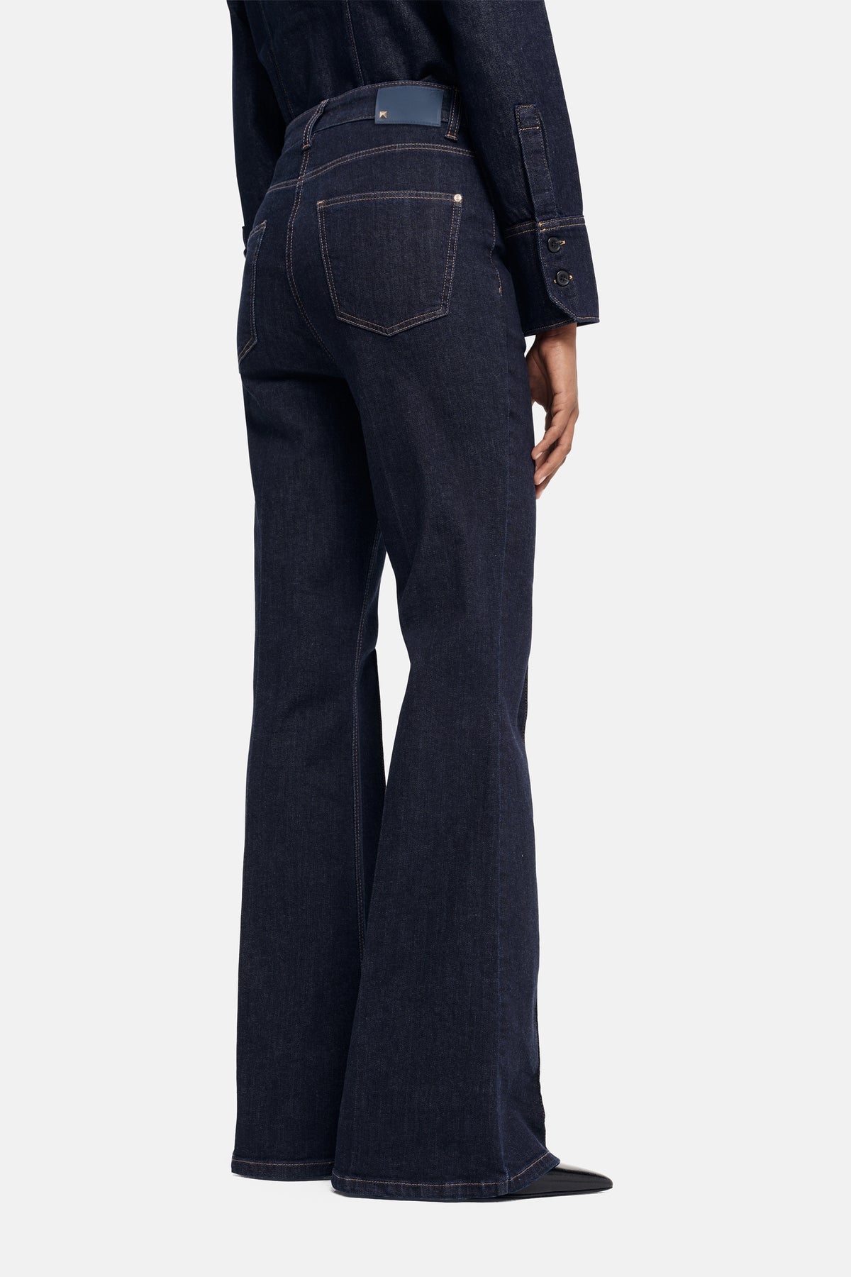 Dunkelblaue flared-fit Jeans aus 93 % Baumwolle, 5 % Polyester, 2 % Elasthan. Getragen in einem lässigen, modernen Outfit.