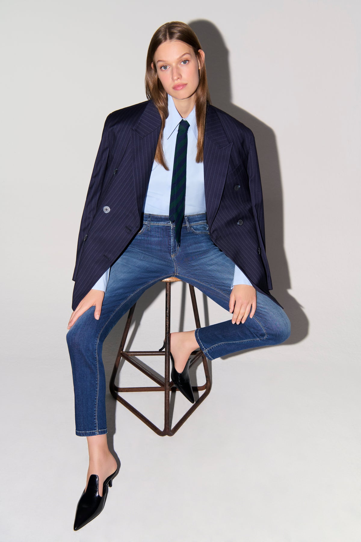 Blaue Slim-Fit-Jeans aus 92% Baumwolle, 6% Elastomultiester T400, 2% Elasthan. Getragen in geschäftlicher Umgebung mit Blazer.