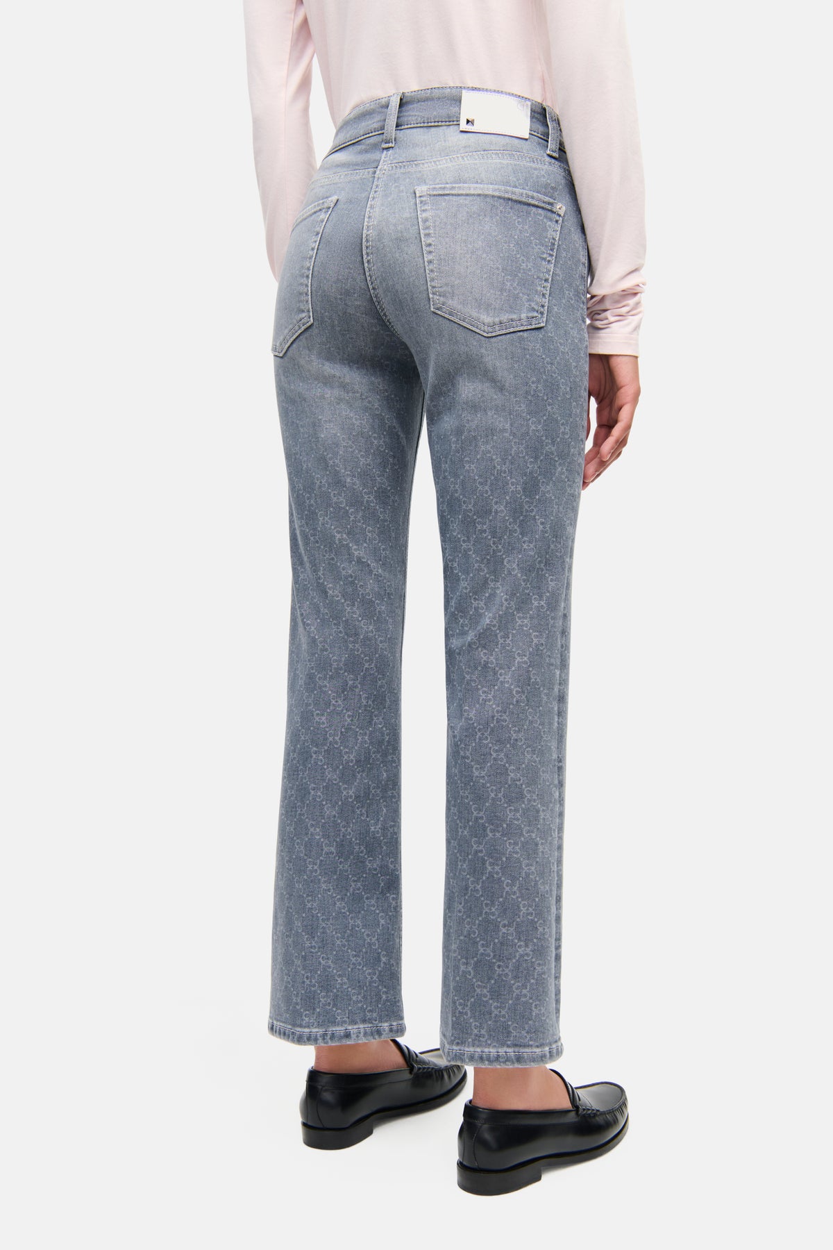 Hellgraue Flared-Fit Cropped Jeans aus 92% Baumwolle, verziert mit gelasertem Kettenmuster, getragen in urbanem Setting.