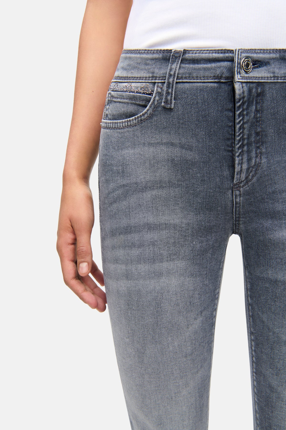 Graue Slim-Fit Jeans aus 92% Baumwolle, mit Strass-Details an der Vordertasche. Im urbanen Setting getragen.