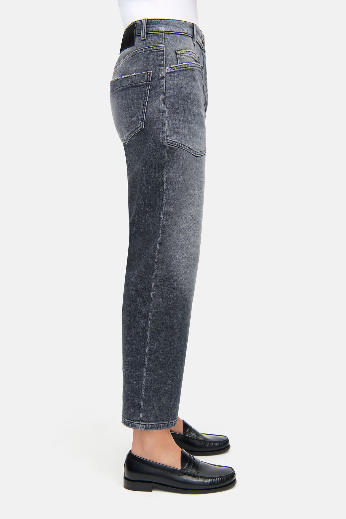 Graue Jeans in O-Form aus 98% Baumwolle und 2% Elasthan. Getragen von einer Person mit schwarzen Loafers.