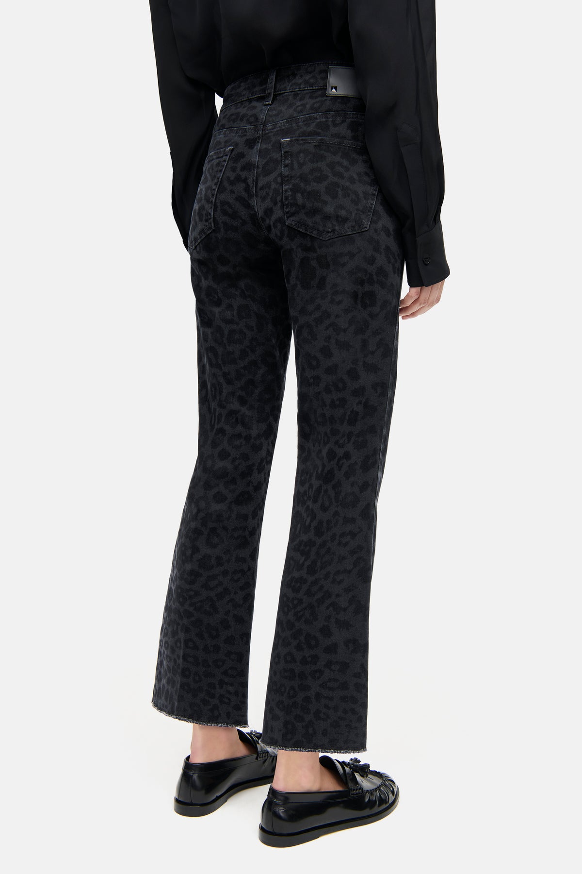 Schwarze, verkürzte Flared-Jeans aus 92% Baumwolle mit Leo-Laserdruck, getragen von einer Person in einem legeren Outfit.