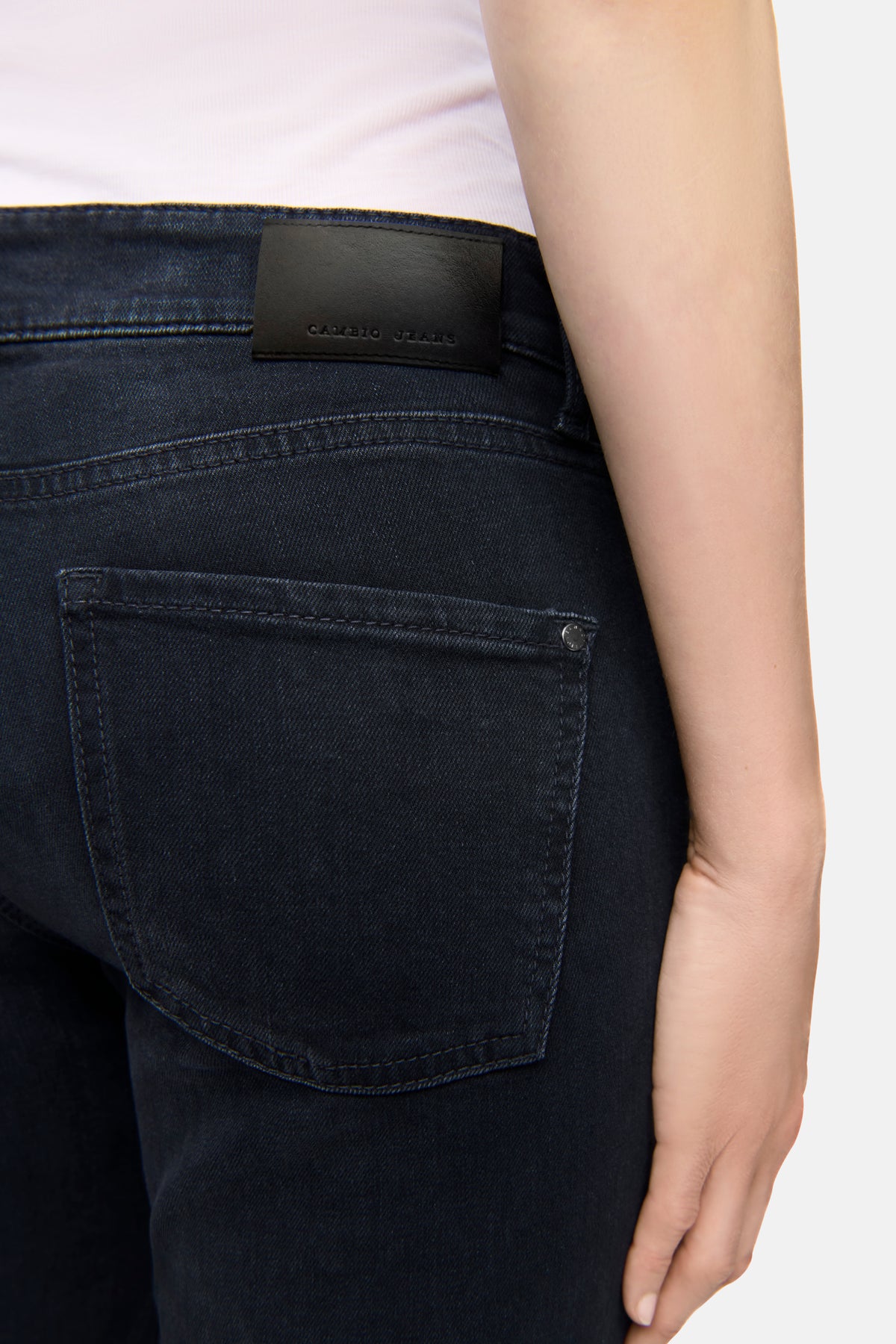 Schwarze Slim-Fit-Jeans aus Superstretch-Material mit 5-Pocket-Design, Nahaufnahme einer Person, die die Jeans trägt.