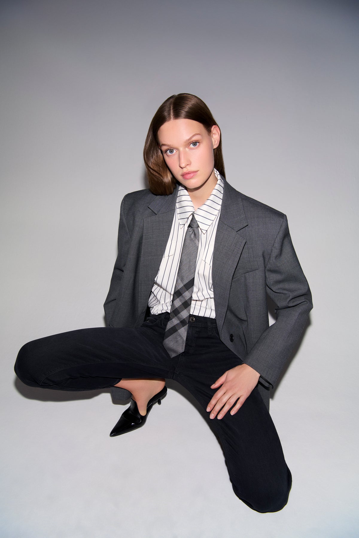 Schwarze Slim-Fit-Jeans aus 57% Baumwolle, 37% Modal, 4% Elastomultiester T400, 2% Elasthan. Person in formeller Kleidung posiert dramatisch.