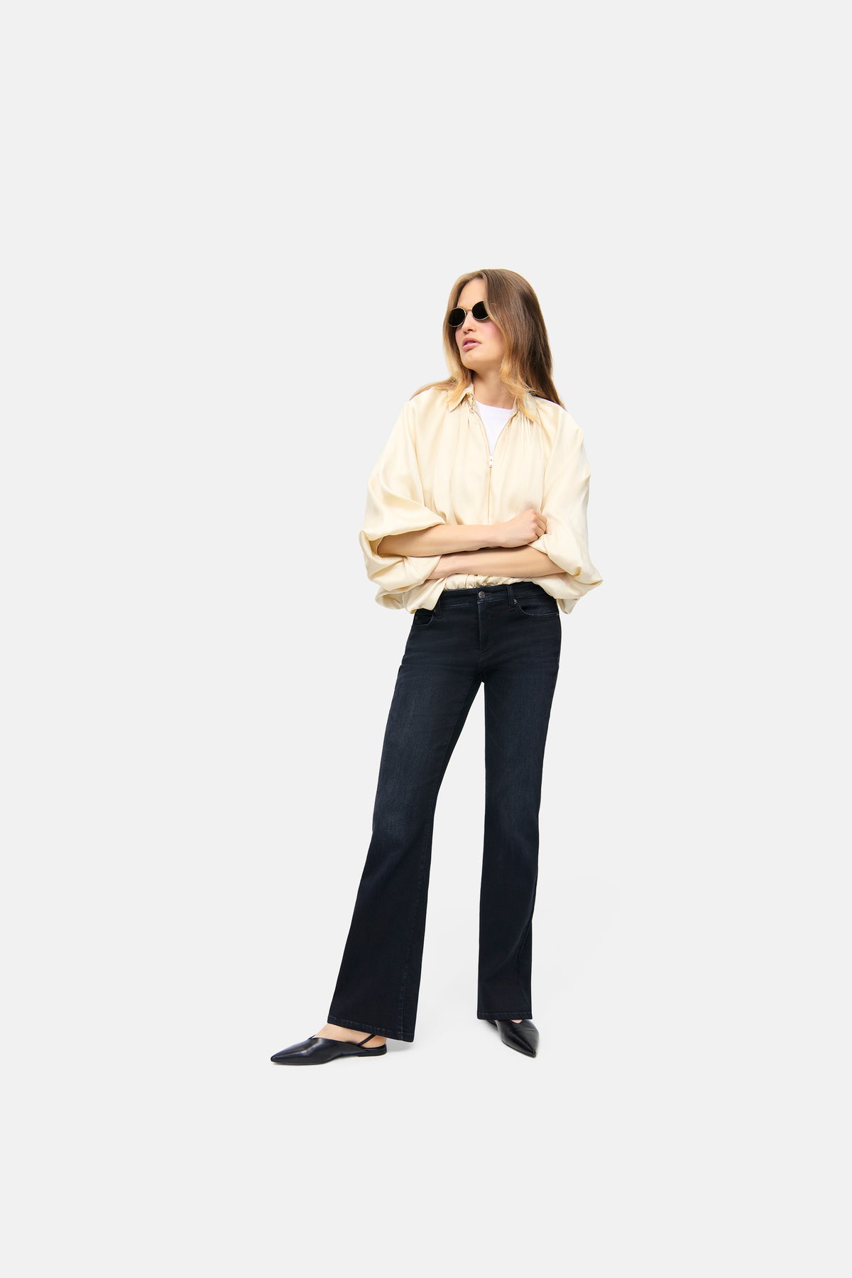 Damen in einem urbanen Setting trägt eine schwarze Flared Jeans aus Stretch-Denim, 81% Baumwolle, 11% Lyocell, 6% Elastomultiester T400, 2% Elasthan.