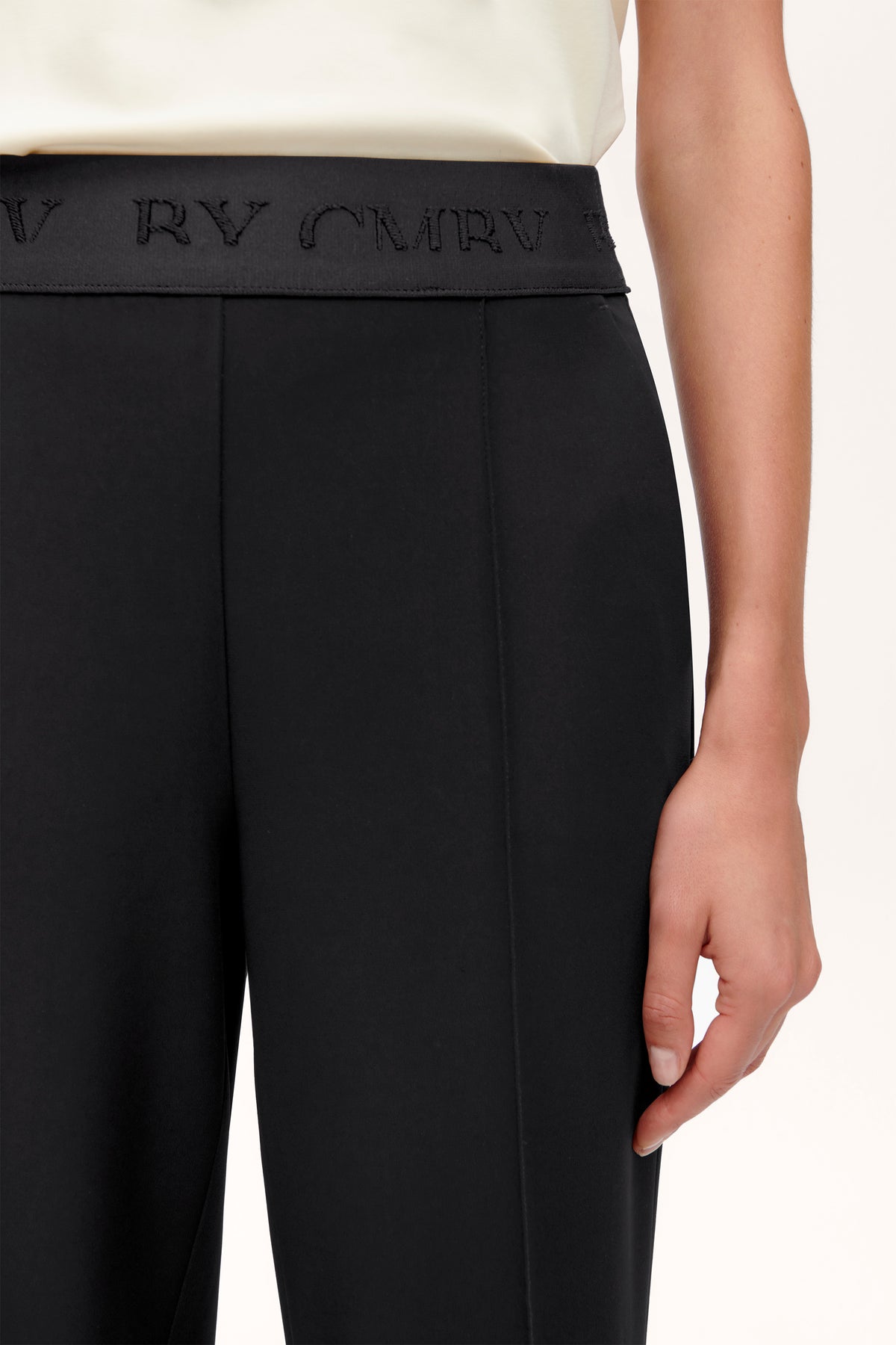 Schwarze Culotte Hose aus 92% Polyester und 8% Polyurethan, mit elastischem Bund. Getragen von einer Person im Innenbereich.